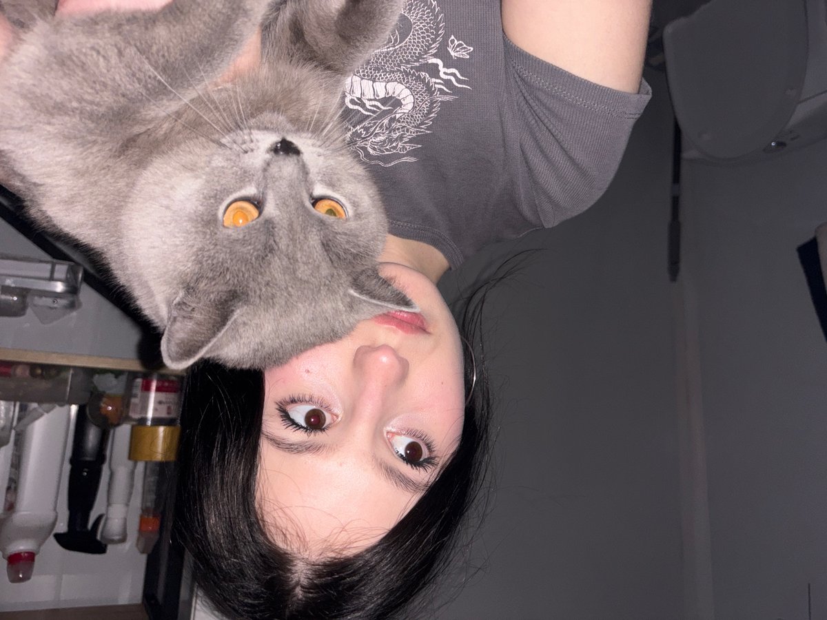 Woman holds gray cat indoors in Russian village