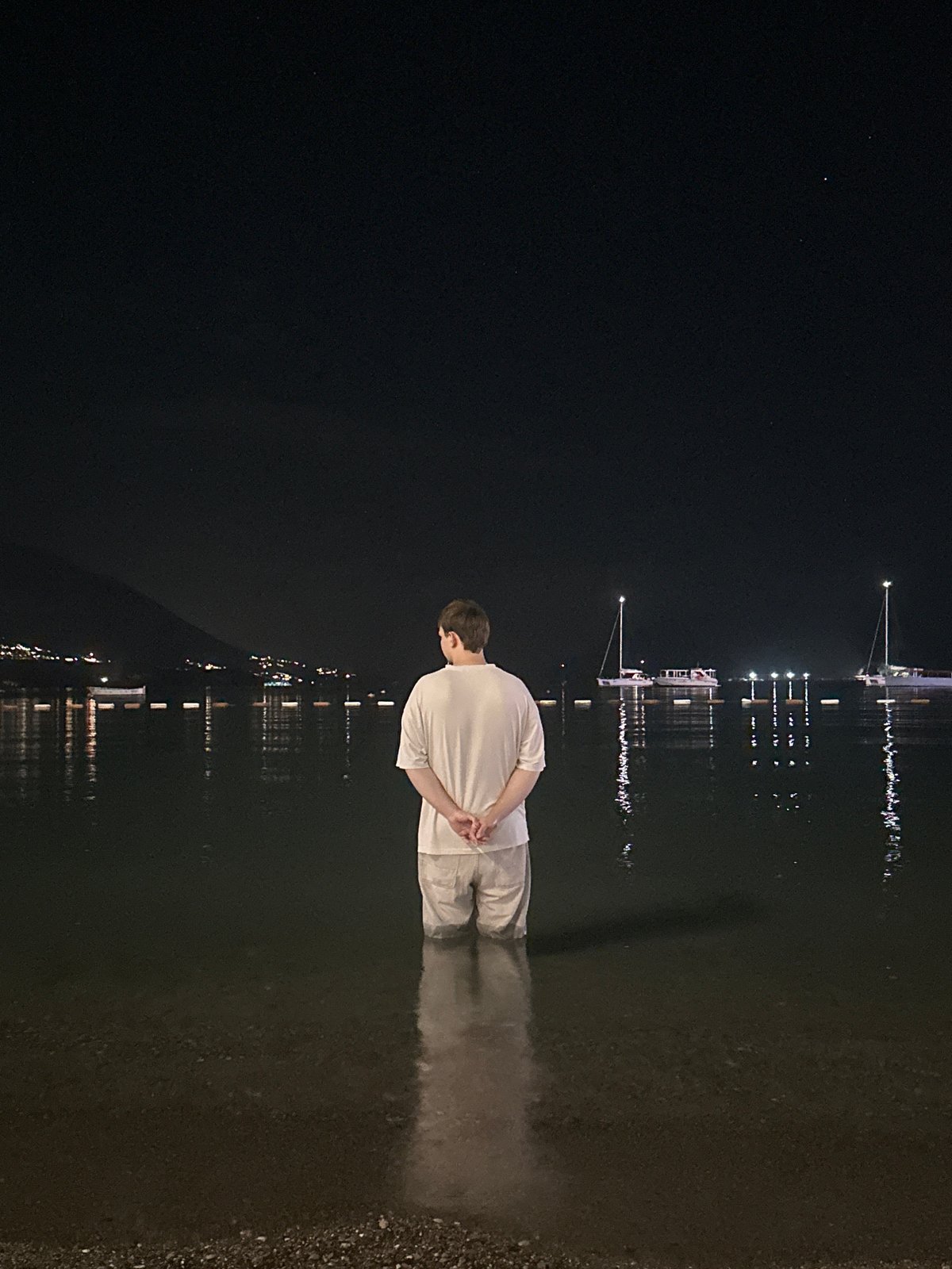 Person stands in nighttime waters off Budva Montenegro coast
