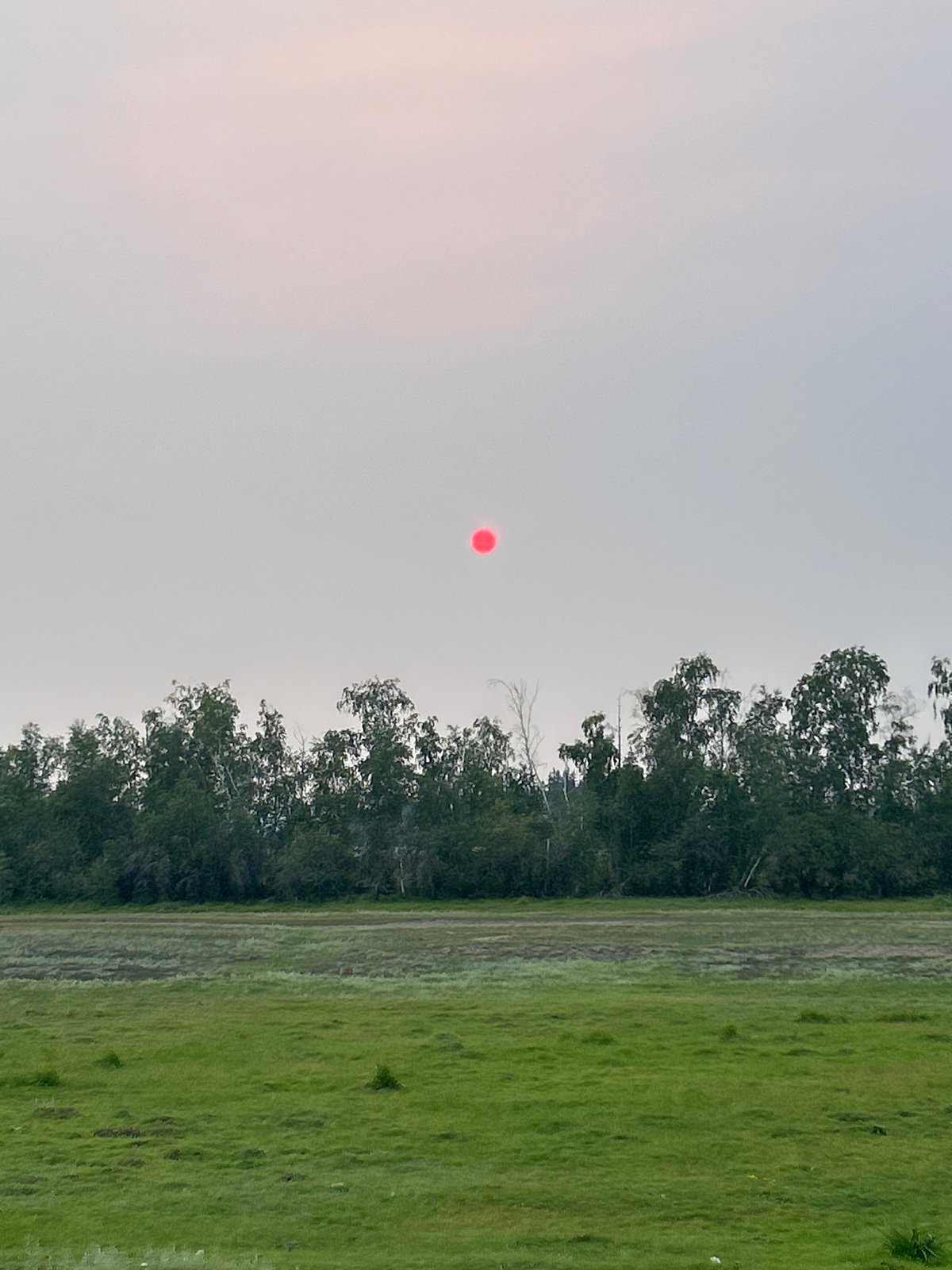 Red sun glows through heavy smoke haze over rural Siberia