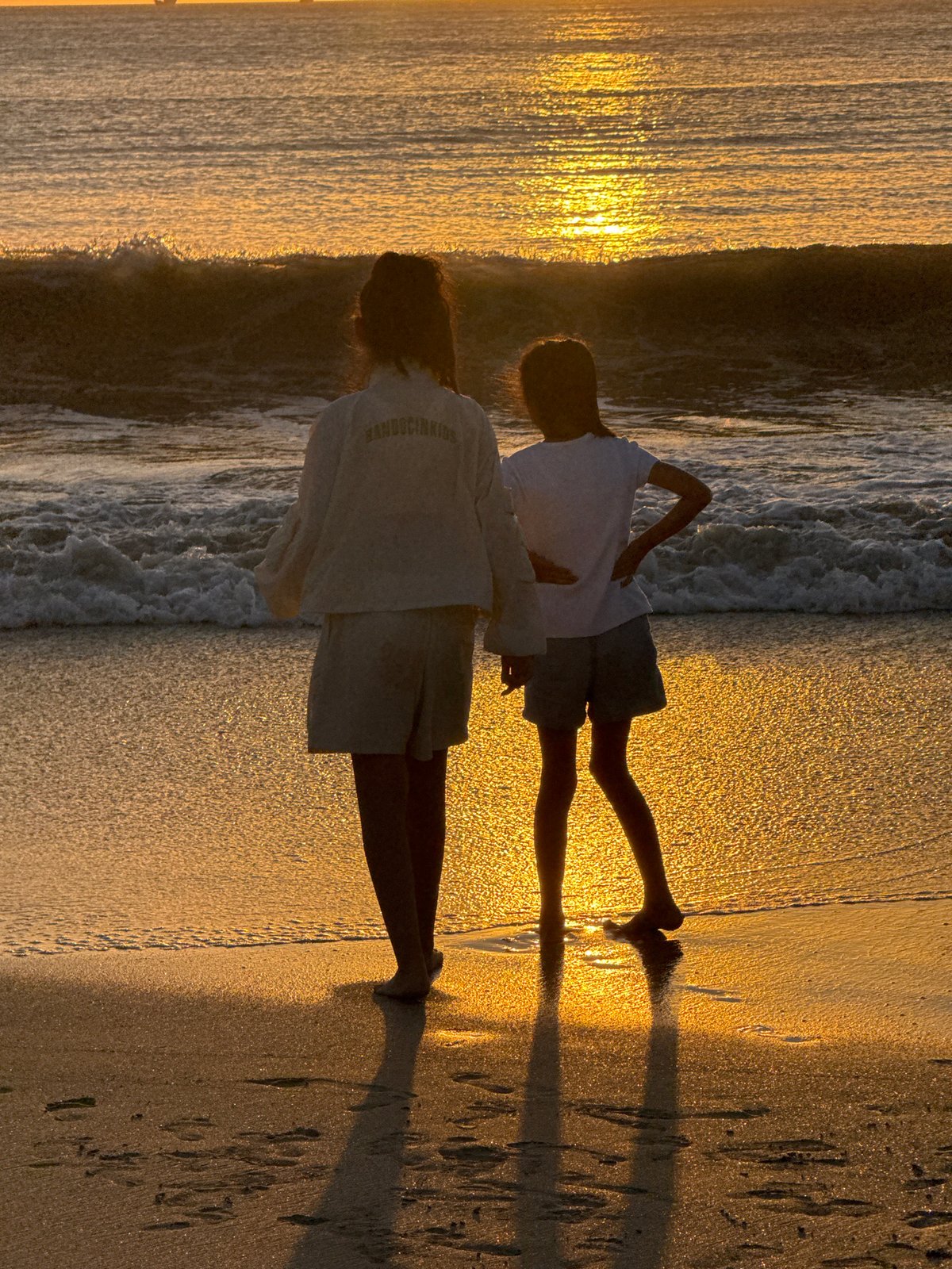 Golden hour on a Kuta Selatan beach, group gathered at the shore