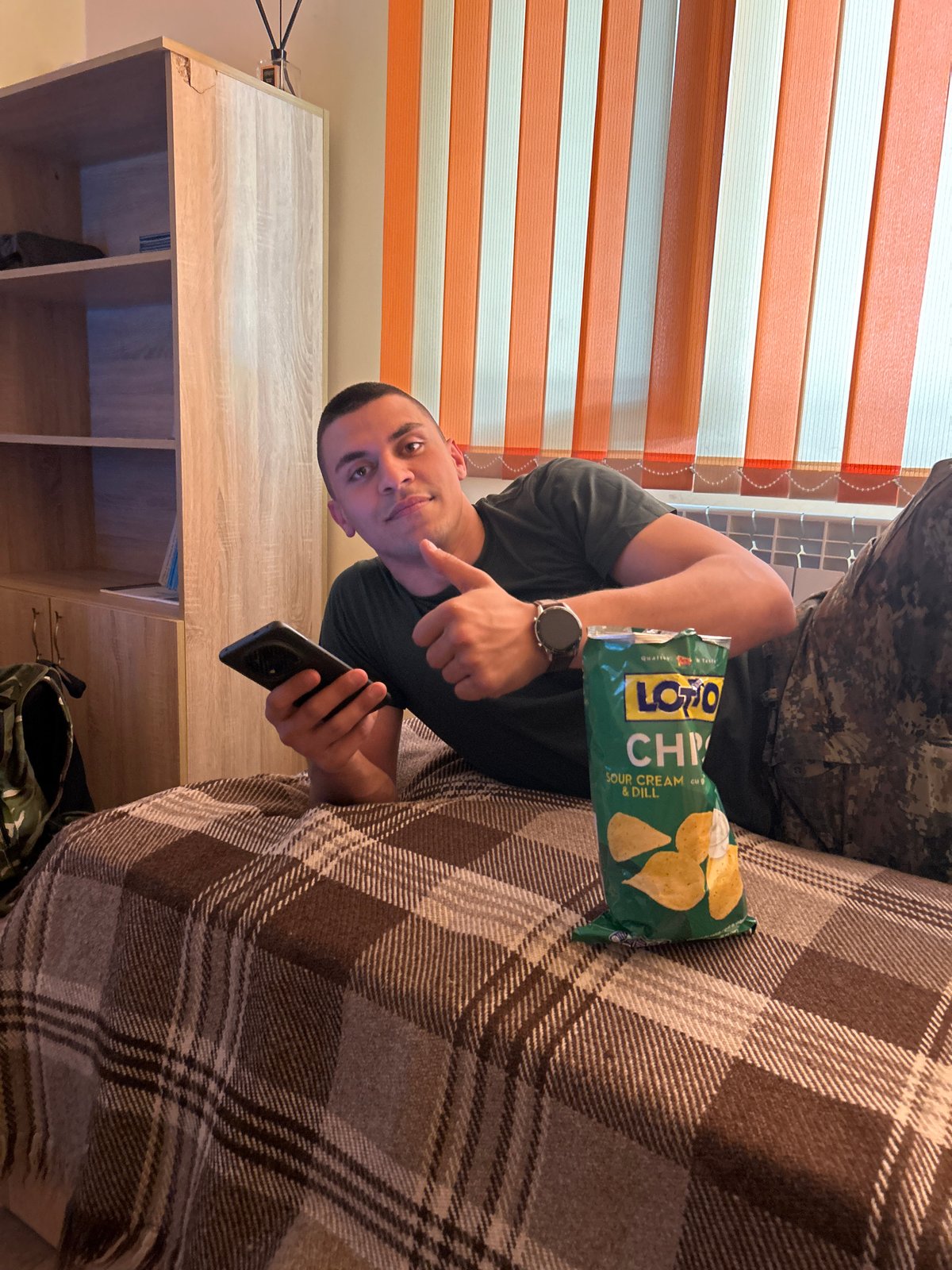 Man with smartphone points while sitting indoors in Shumen