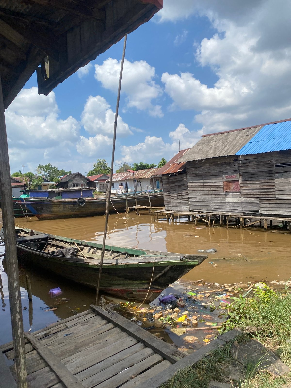 Stilt houses and wooden boats along a muddy Borneo riverbank