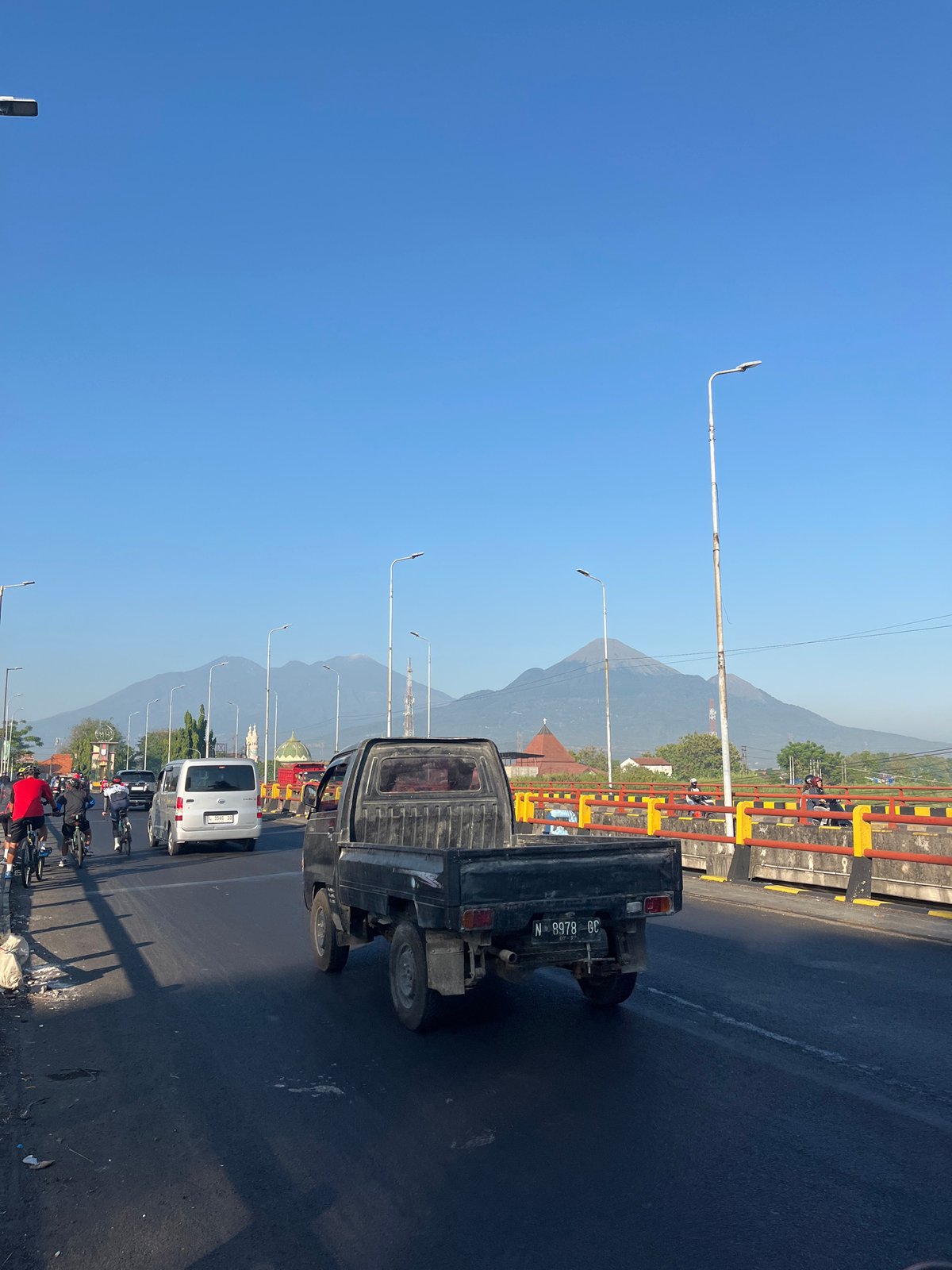 Cyclists and motorcyclists share a bridge route in East Java
