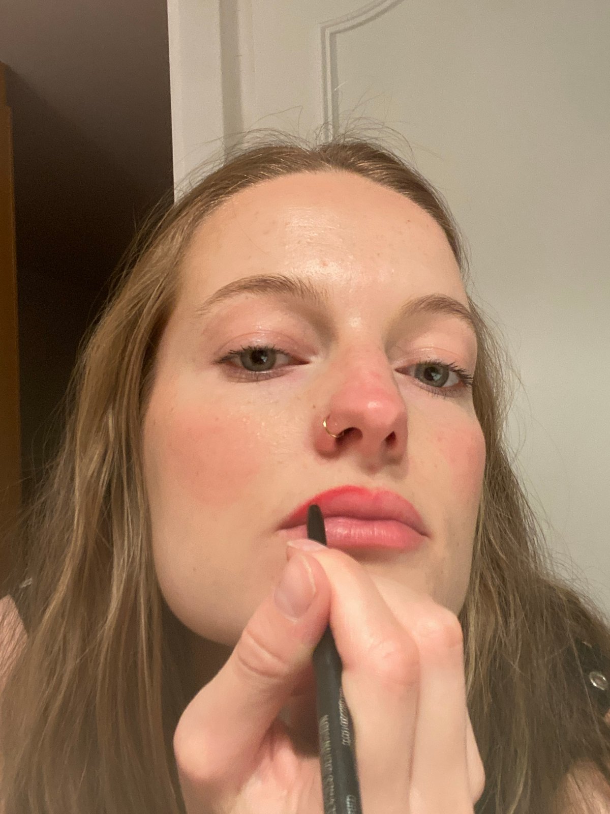 Woman applies red lip liner with eyeliner pencil in Paris