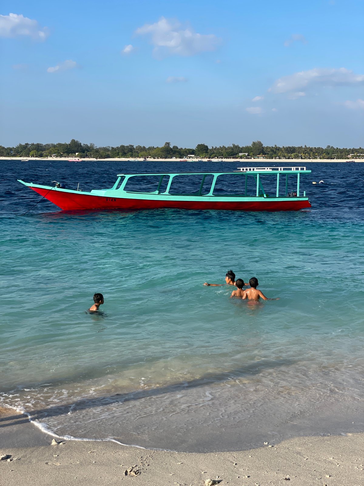Lively tropical beach day with boats, swimmers, and shoreside hangout