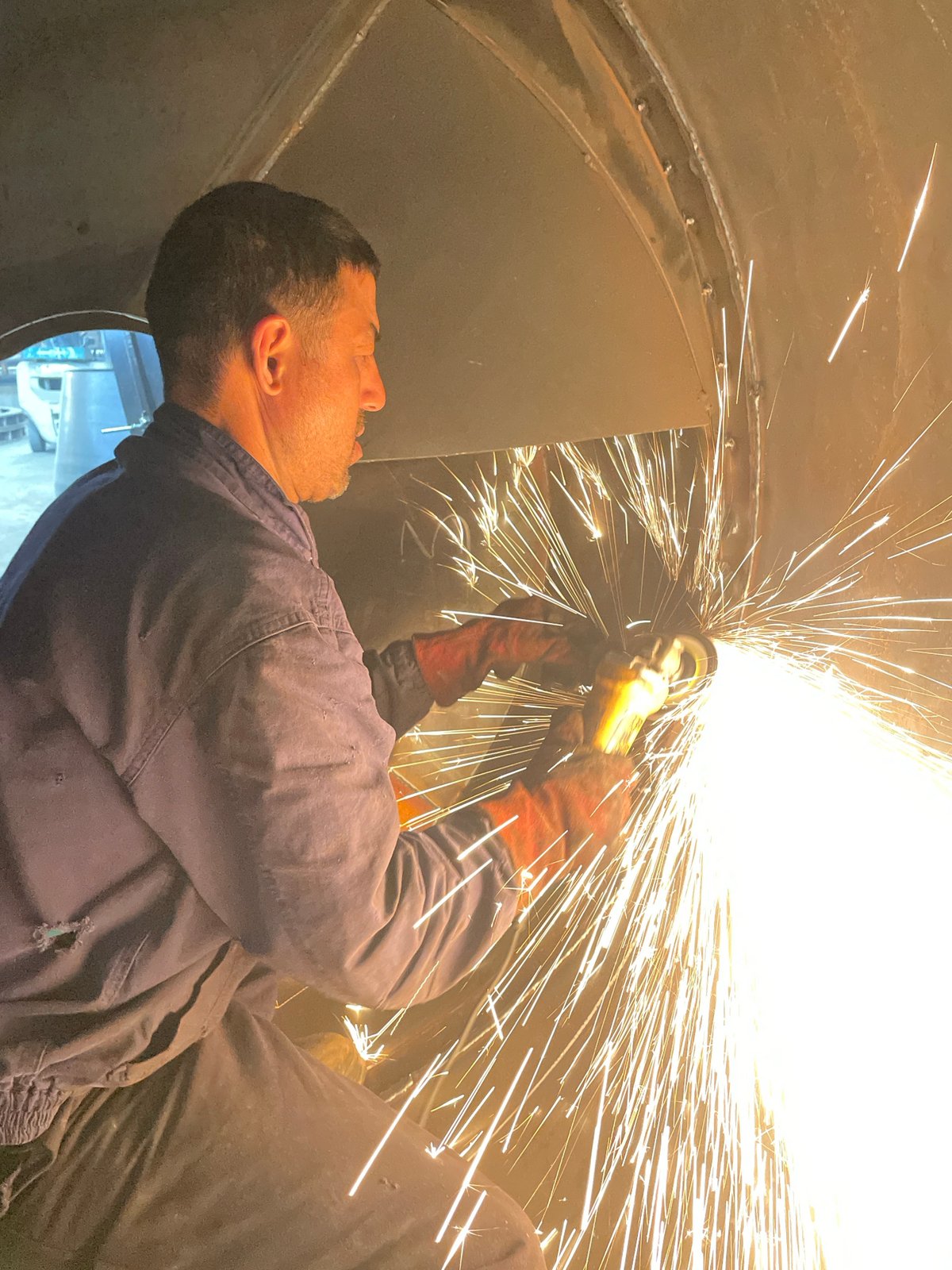 Worker operates angle grinder inside metal structure in Montenegro