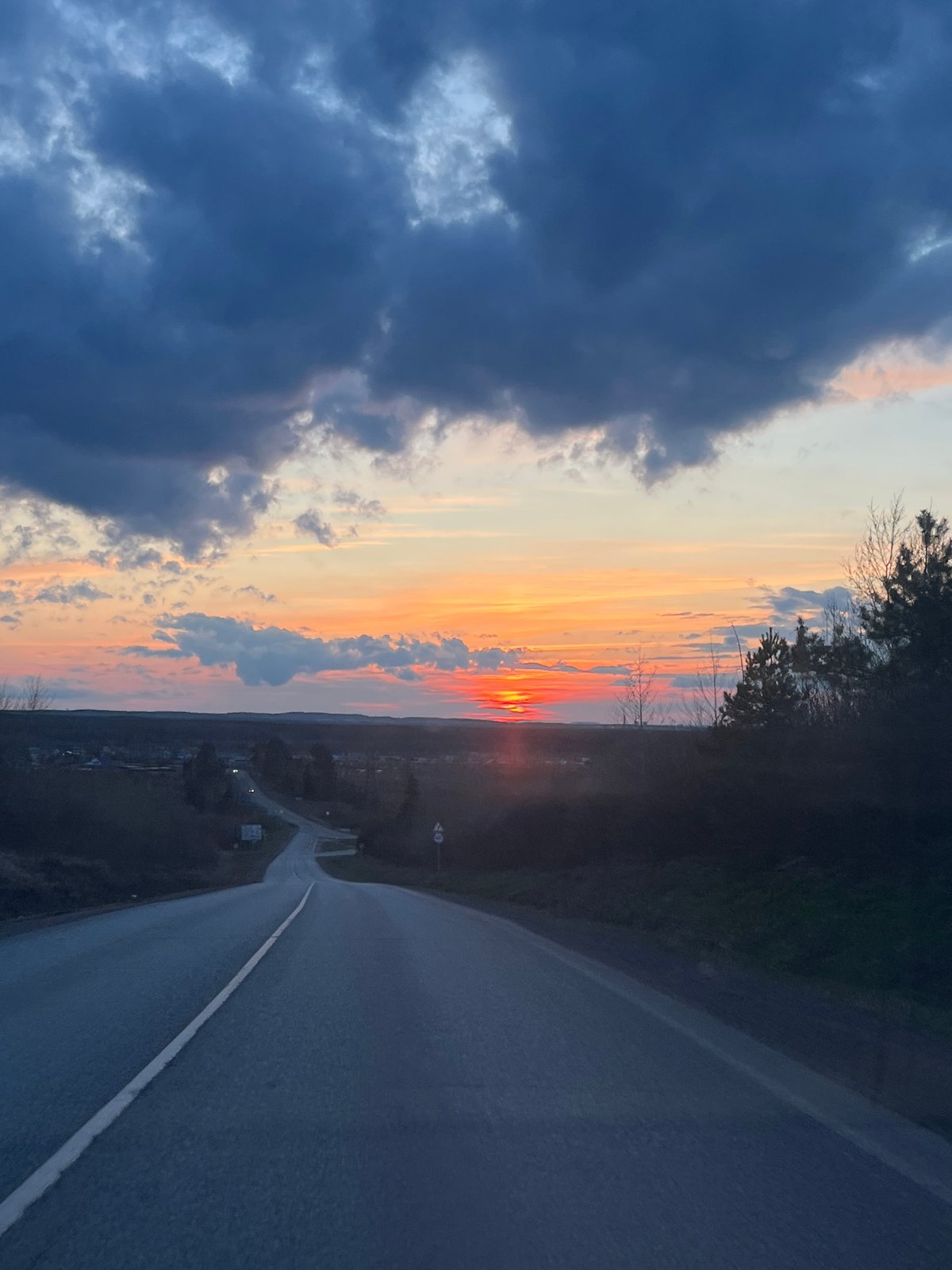 Sunset road scene contrasts storm clouds with vibrant skies