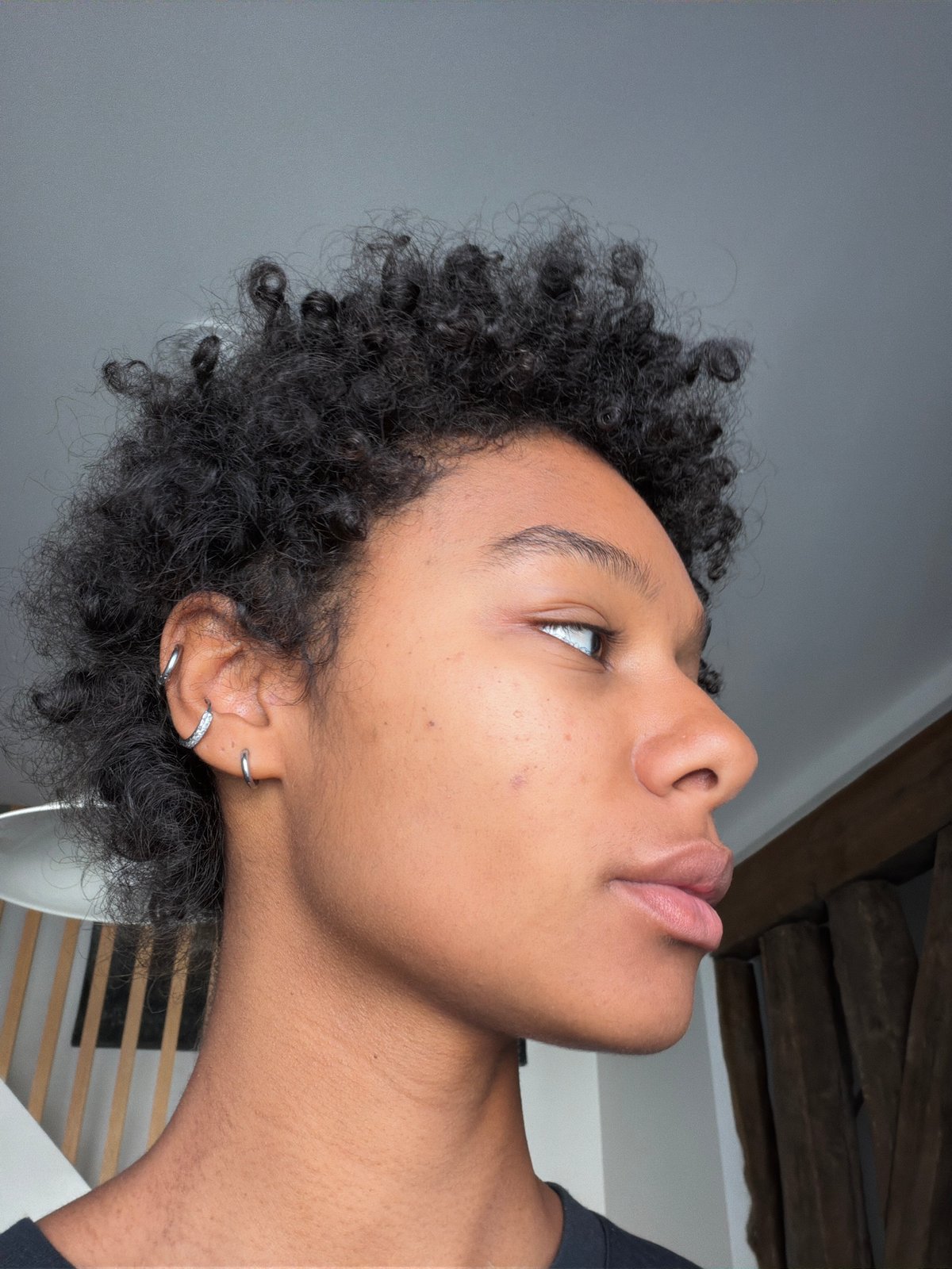 Close-up profile with curly hair and stone-accented hoop earrings, Paris