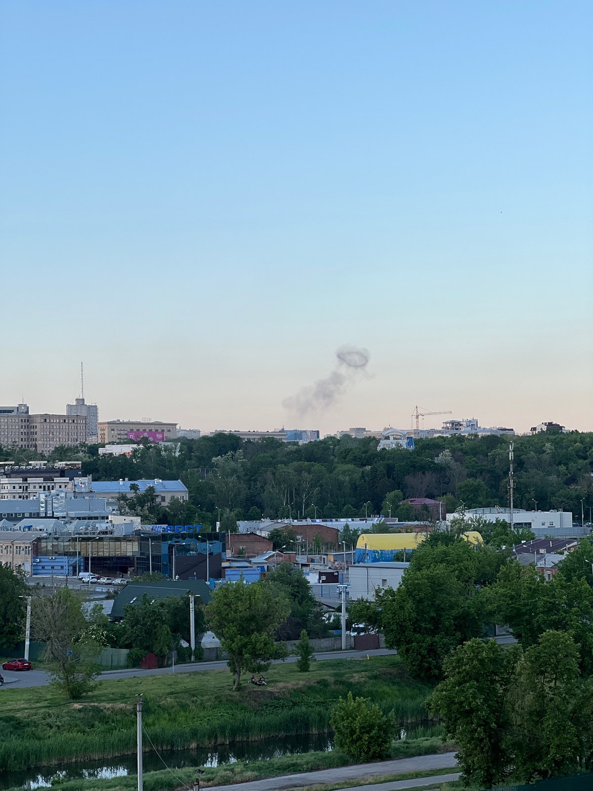 Ring-shaped smoke column observed over city skyline during evening