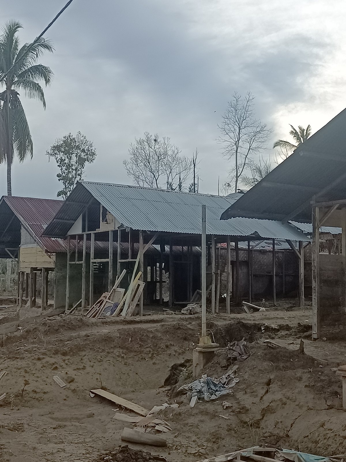 Damaged buildings with exposed framing and wrecked metal roofing
