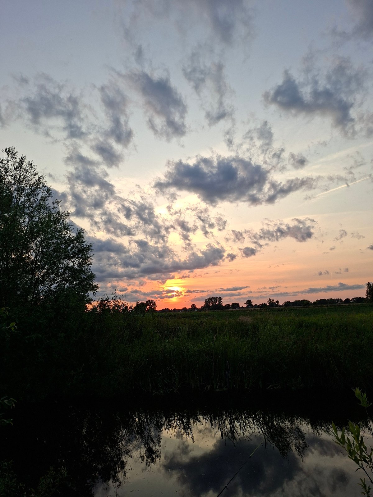Quiet sunset over still water, sky shifting through dusk colors
