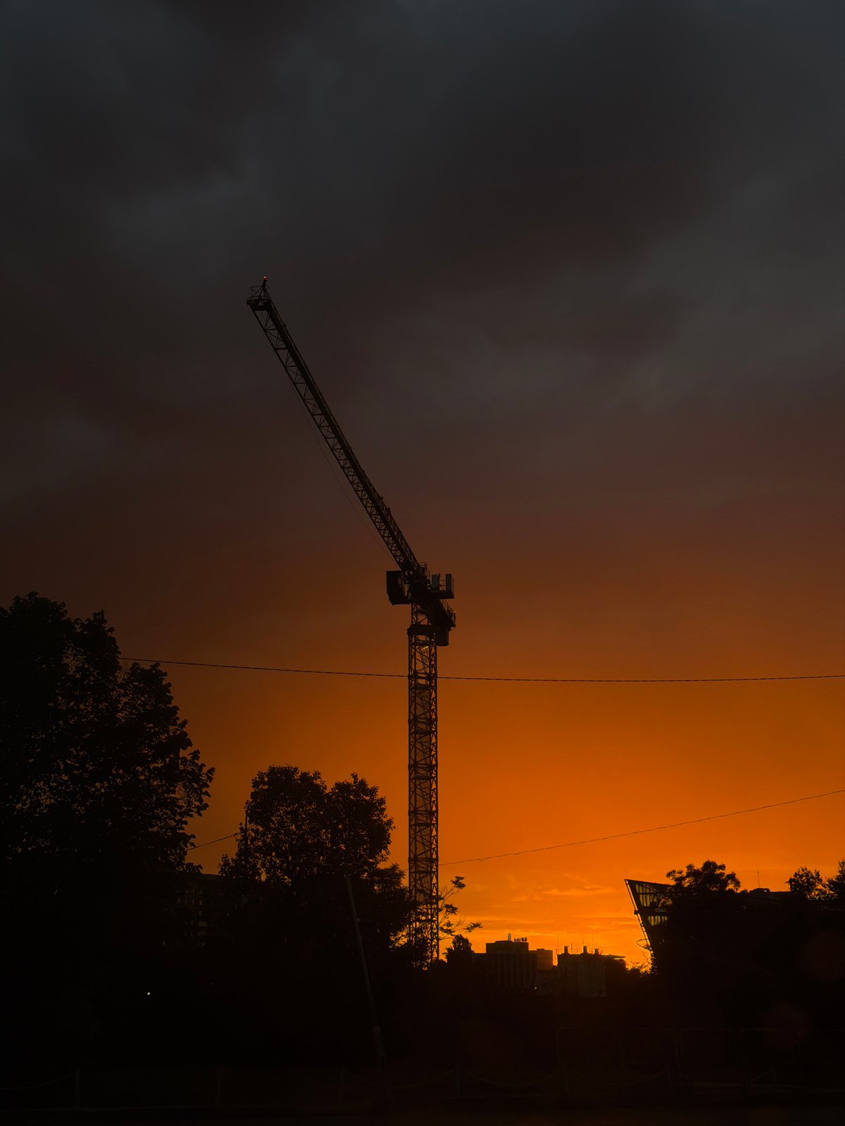 Dramatic sunset silhouettes construction crane over Sofia skyline