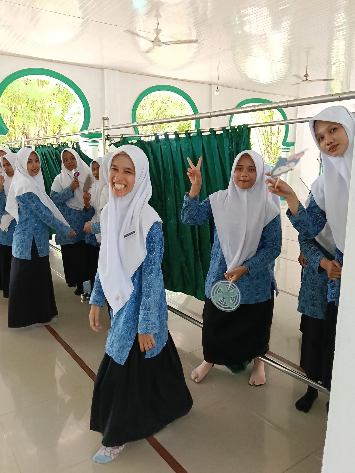 Students and teacher pose in Indonesian school hallway