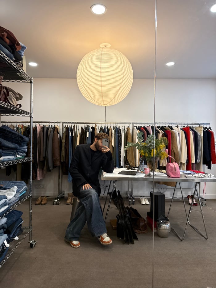 Man shops at Paris boutique amid clothing racks and mirrors