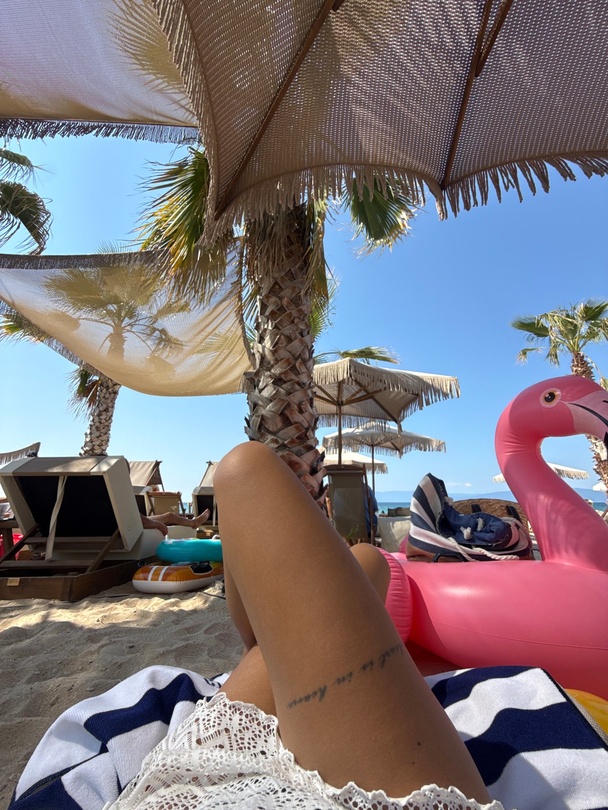 Relaxed morning at Ofrynio Beach under palm trees and umbrellas