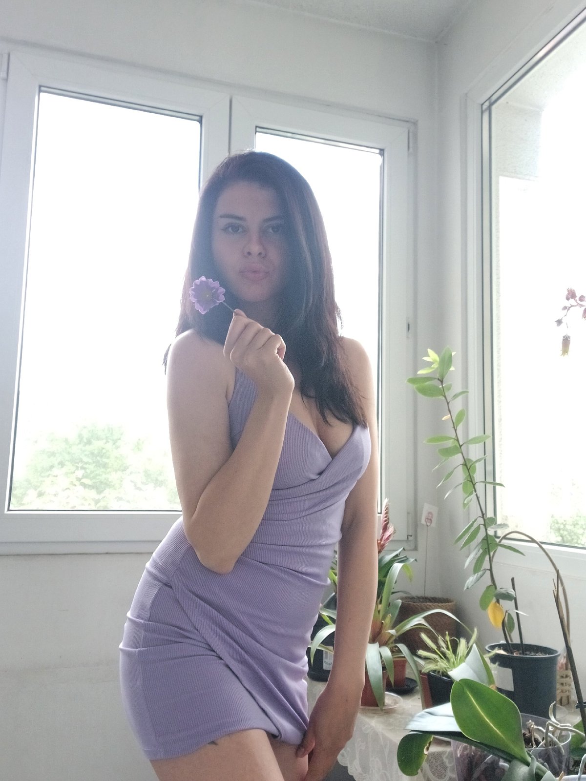 Woman poses with purple flower in Sofia apartment