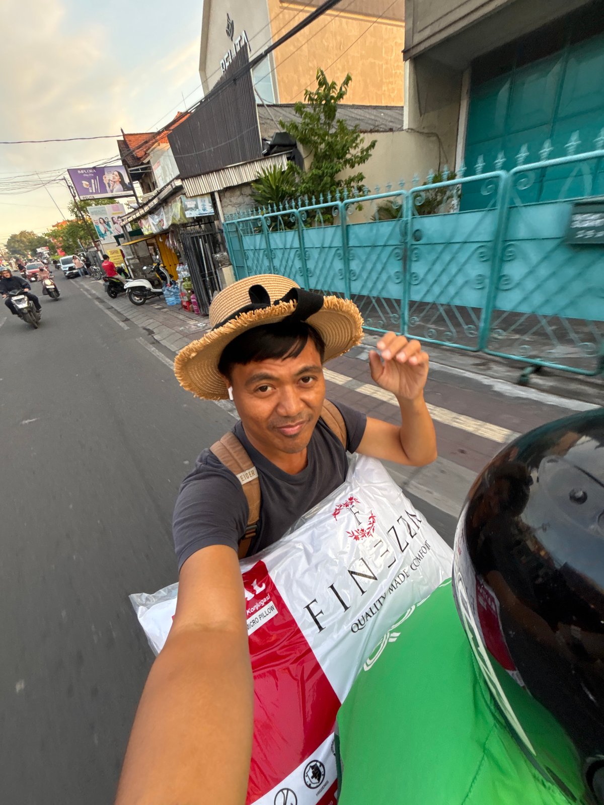 Motorcycle rider hauling a pillow bag through Denpasar streets