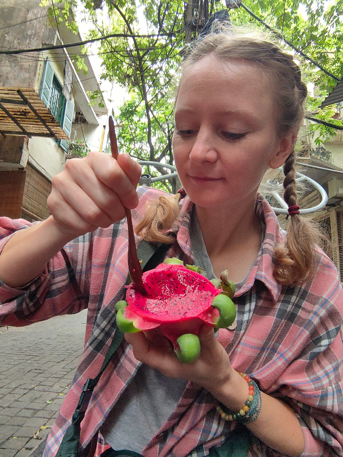 Tourist enjoys dragon fruit at busy Hanoi street market