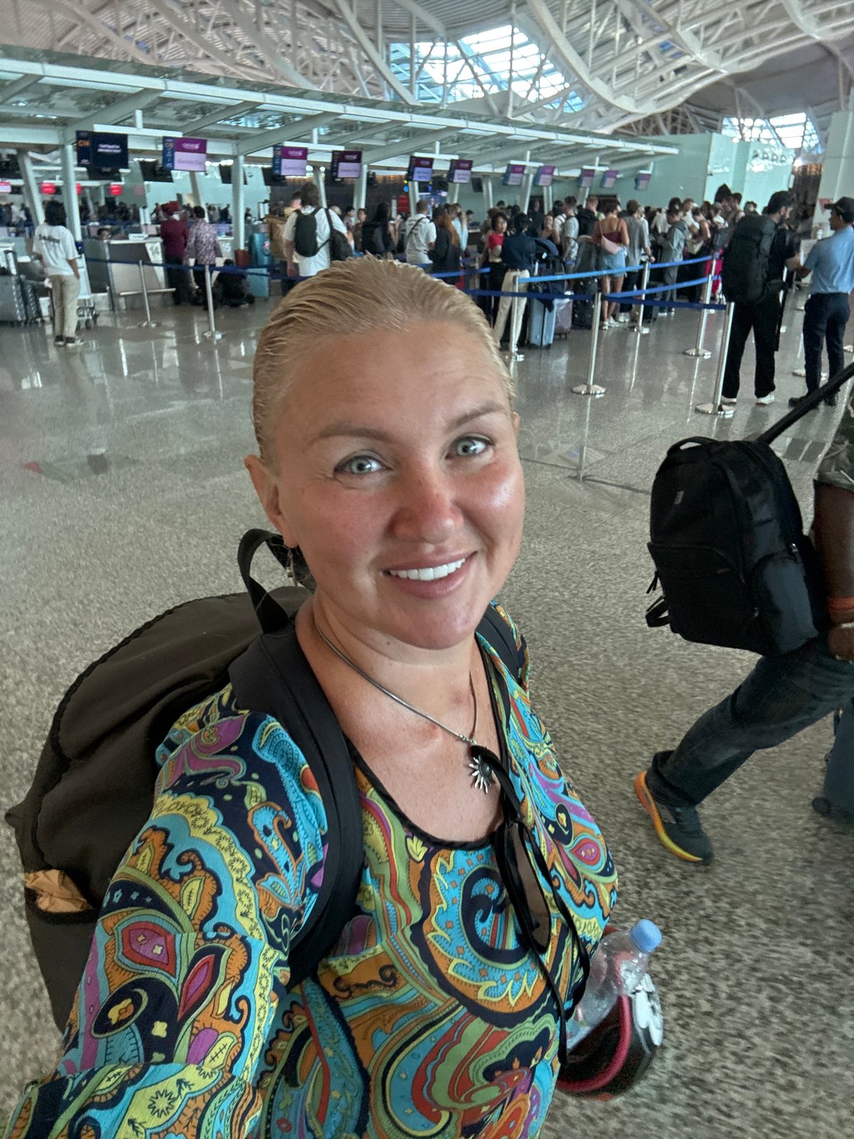 Mother and child navigate Bali airport with luggage cart