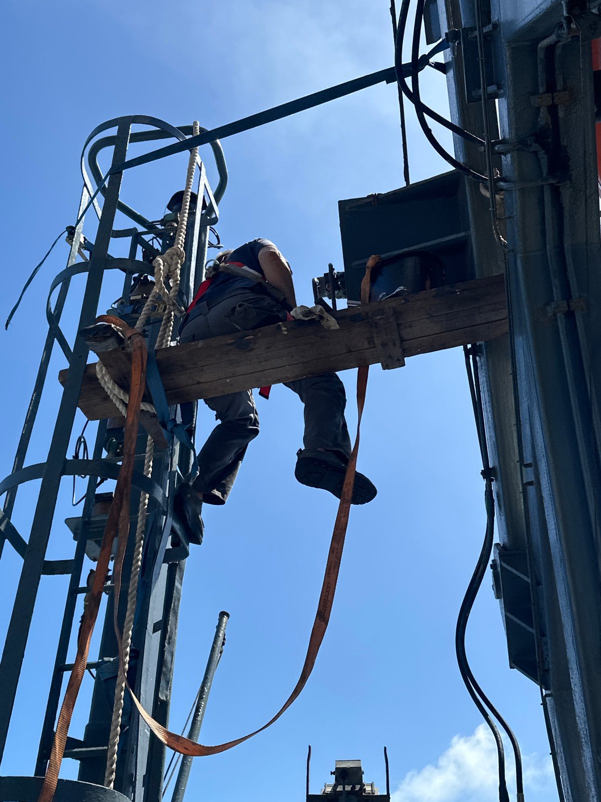 Harnessed worker suspended during aerial structure operations