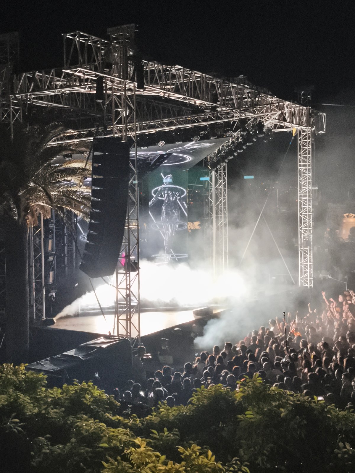 Large crowd enjoys outdoor nighttime concert with stage effects