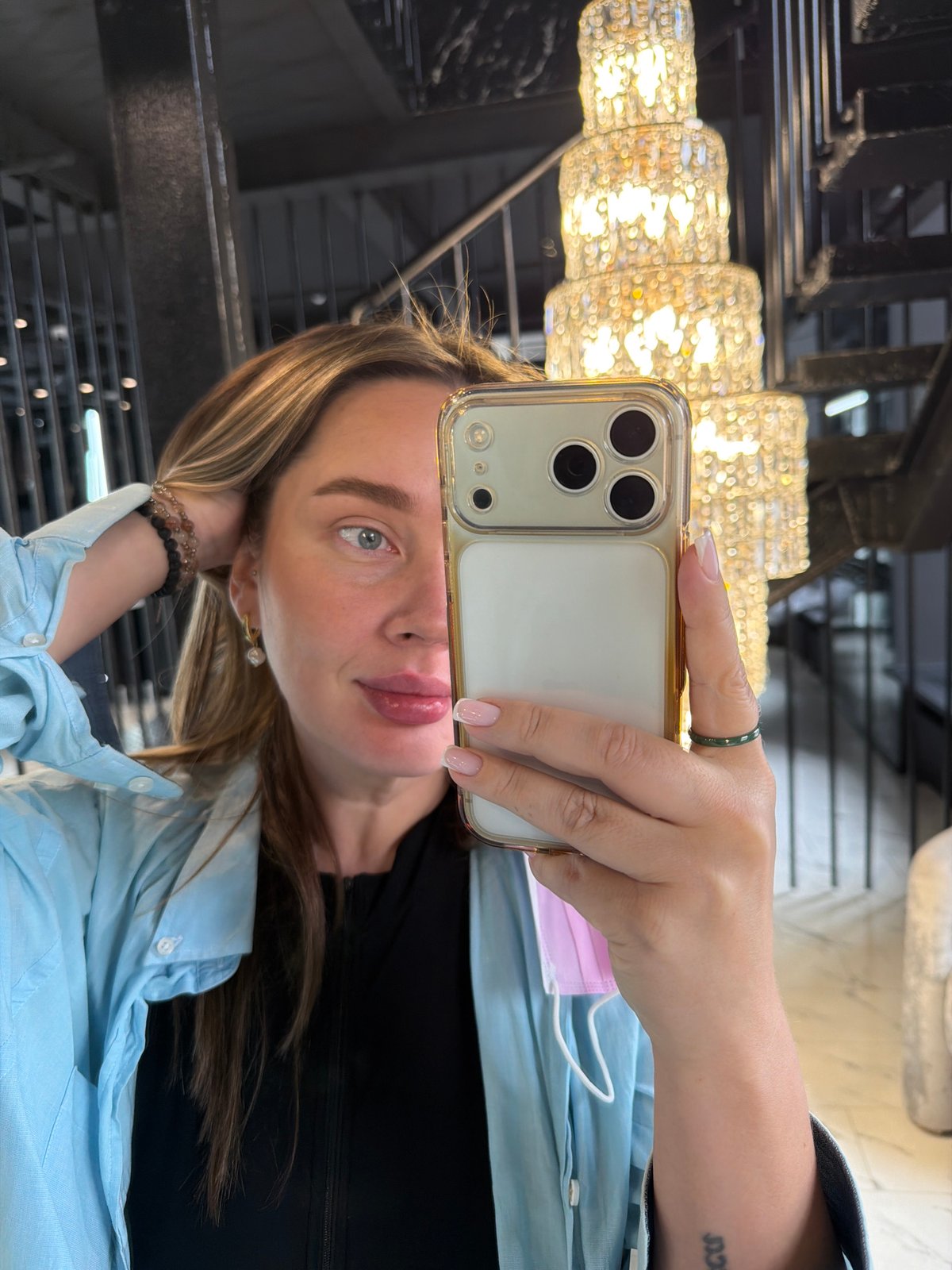 Woman takes chandelier selfie with gold iPhone in Moscow
