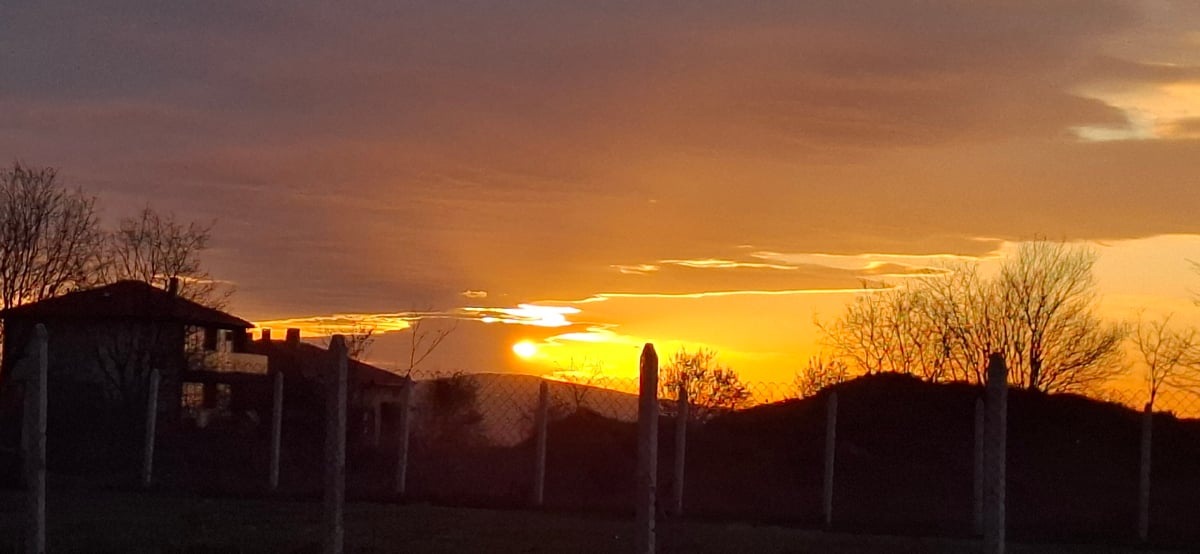 Sunset observed with silhouetted buildings in rural area