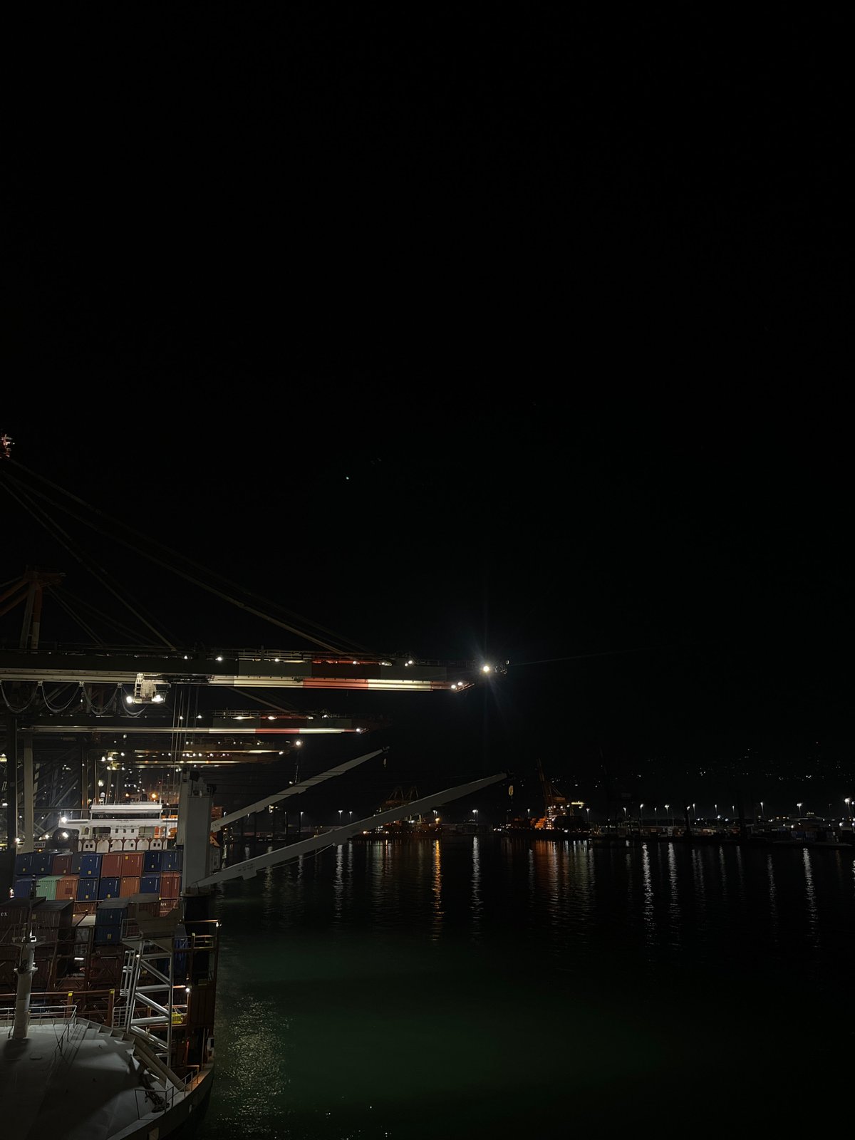 Illuminated cargo ship observed at nighttime port operations