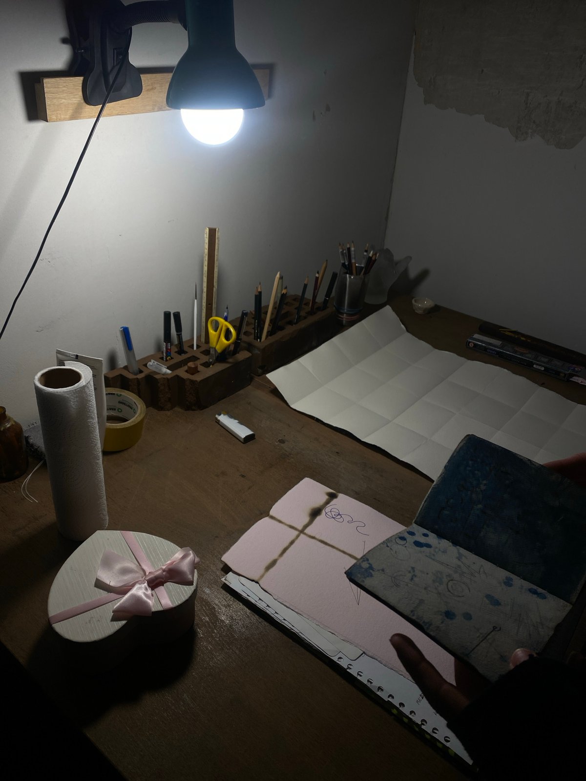 Art workspace documented under desk lamp in Moscow