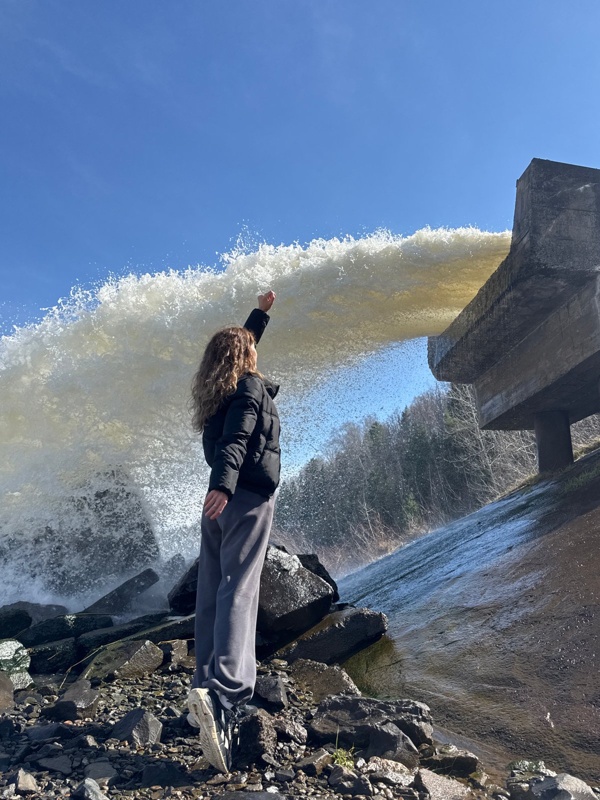 Person poses at waterfall base in Noviy, Russia