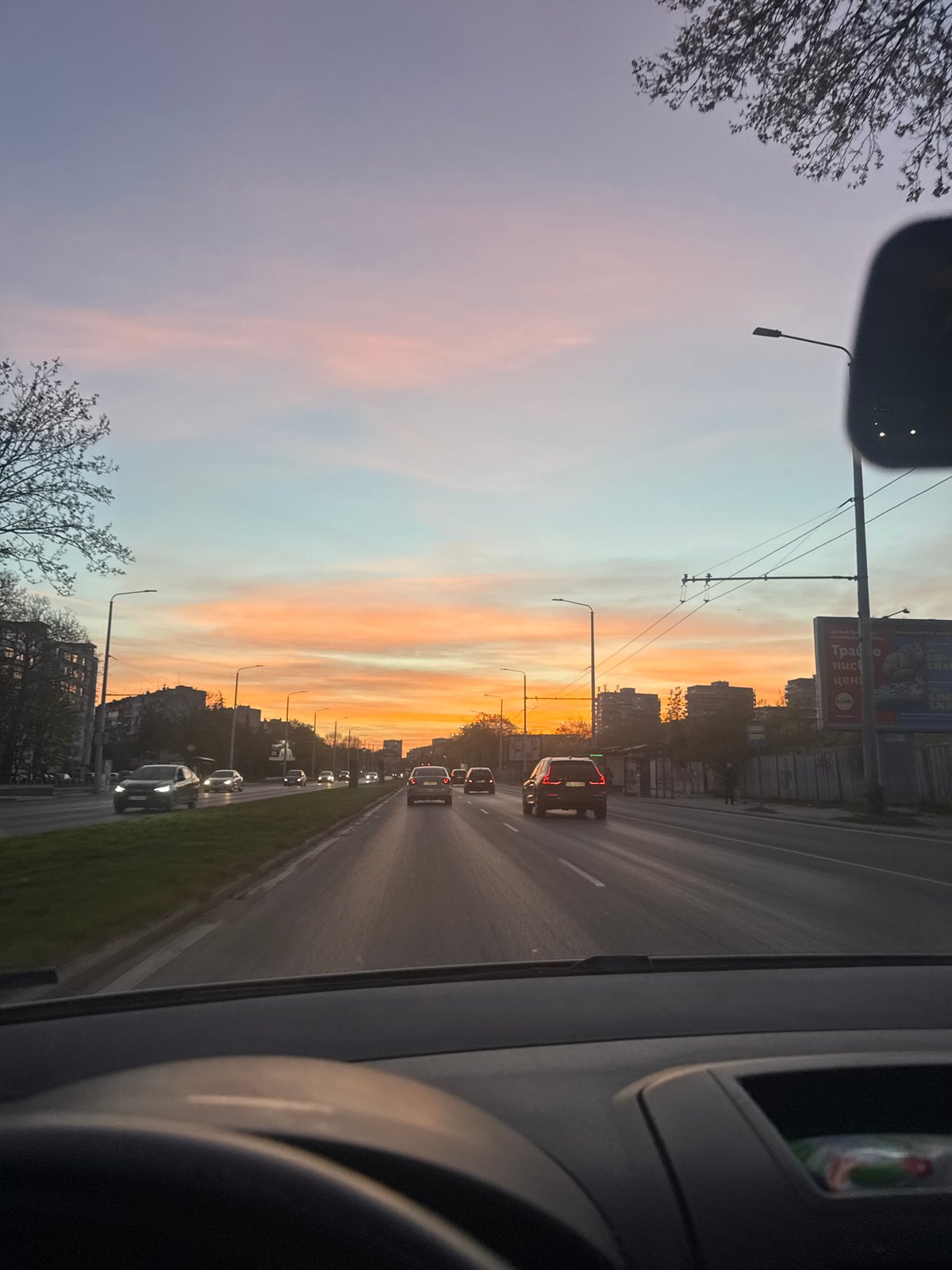 Vehicle passenger captures street scene during golden hour in Varna