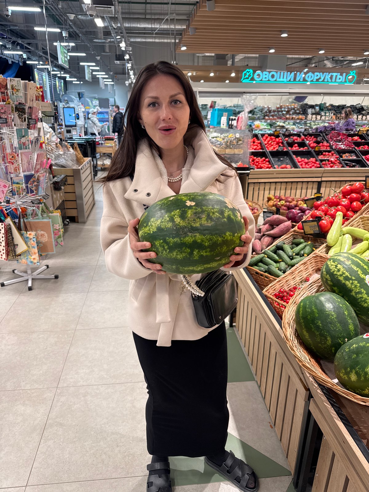 Woman shops for watermelon in grocery store produce section