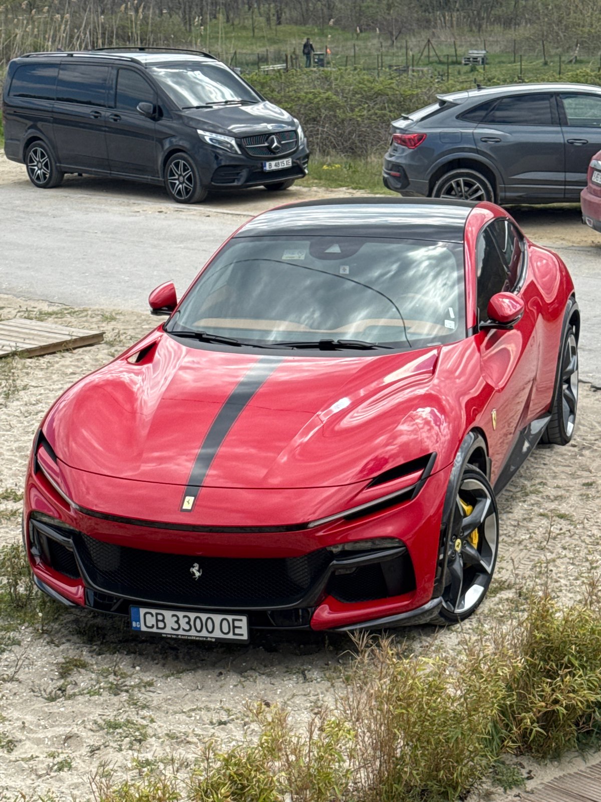 Red Ferrari parks alongside dirt path in Varna