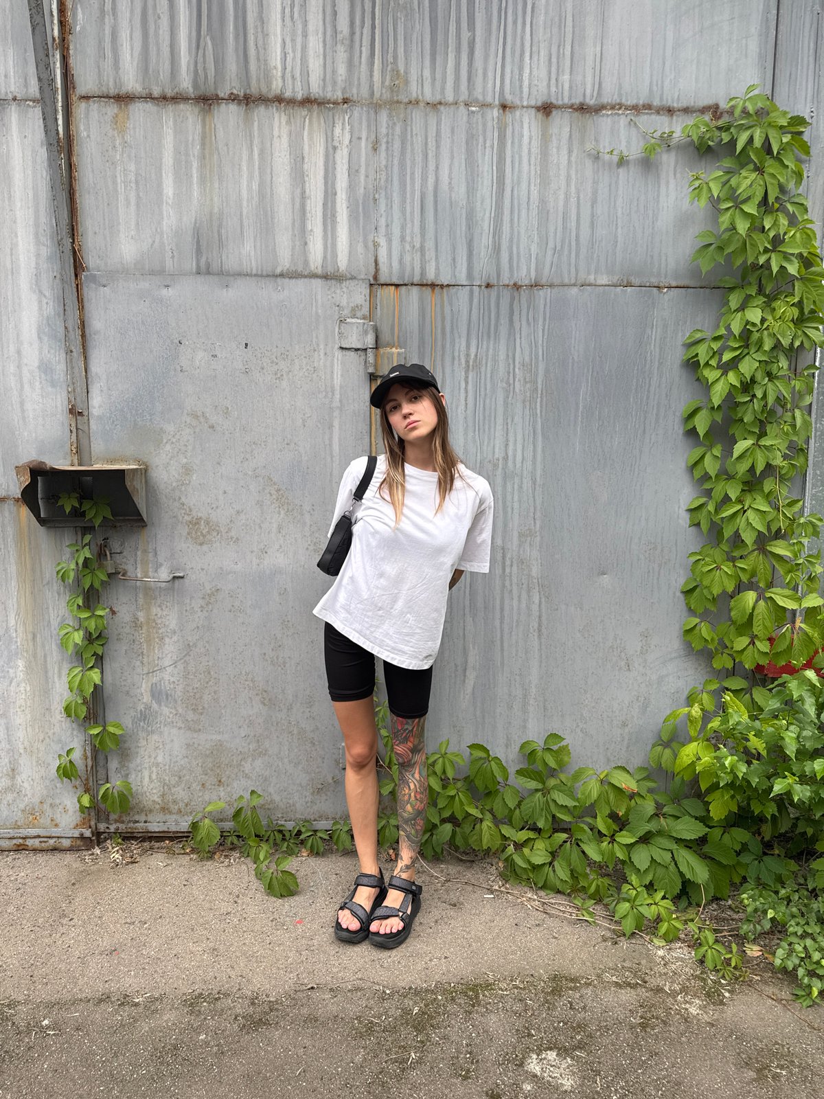 Tattooed figure poses against rusty corrugated wall in Moscow