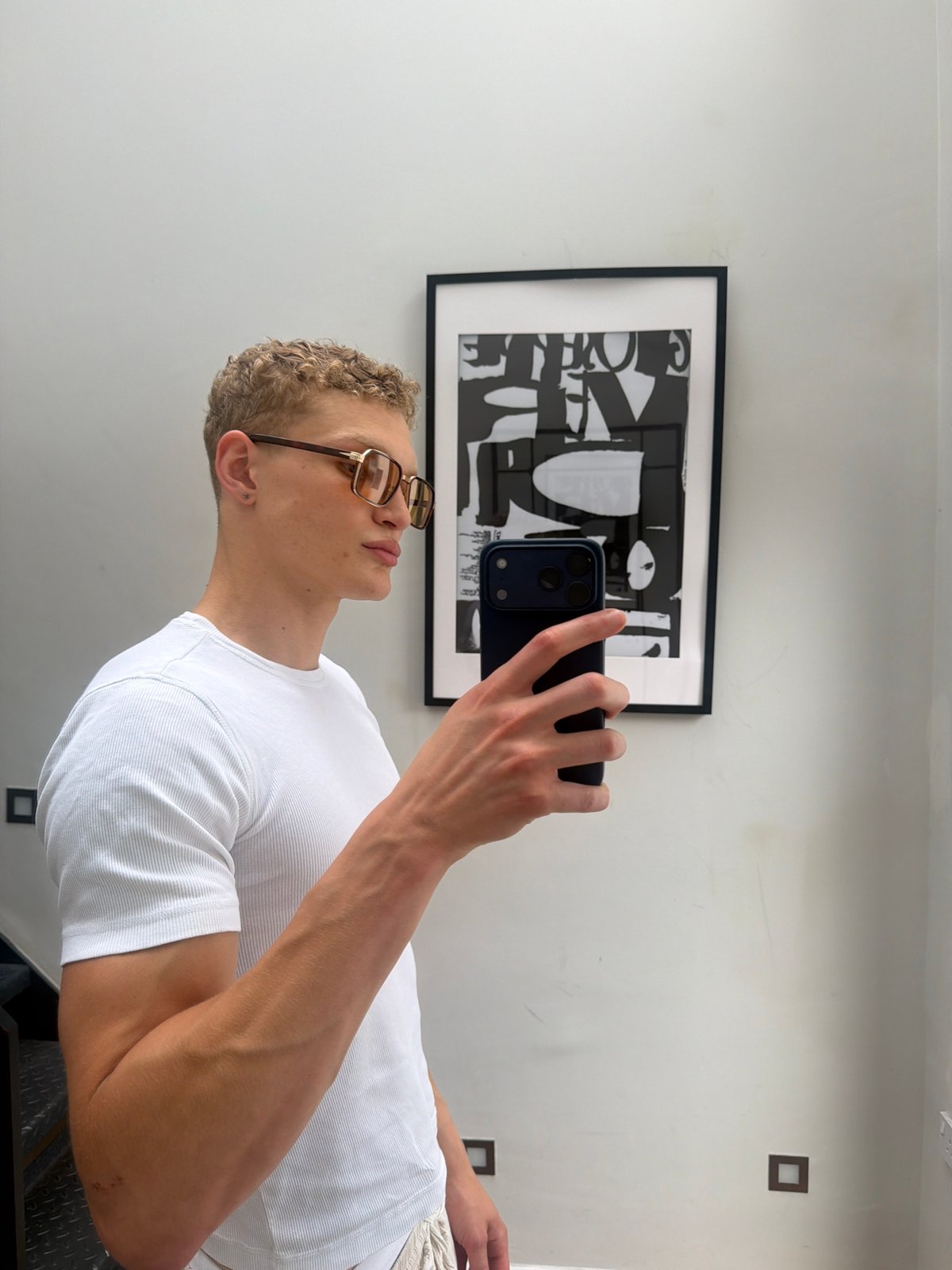 Mirror selfie in a minimal white room, London