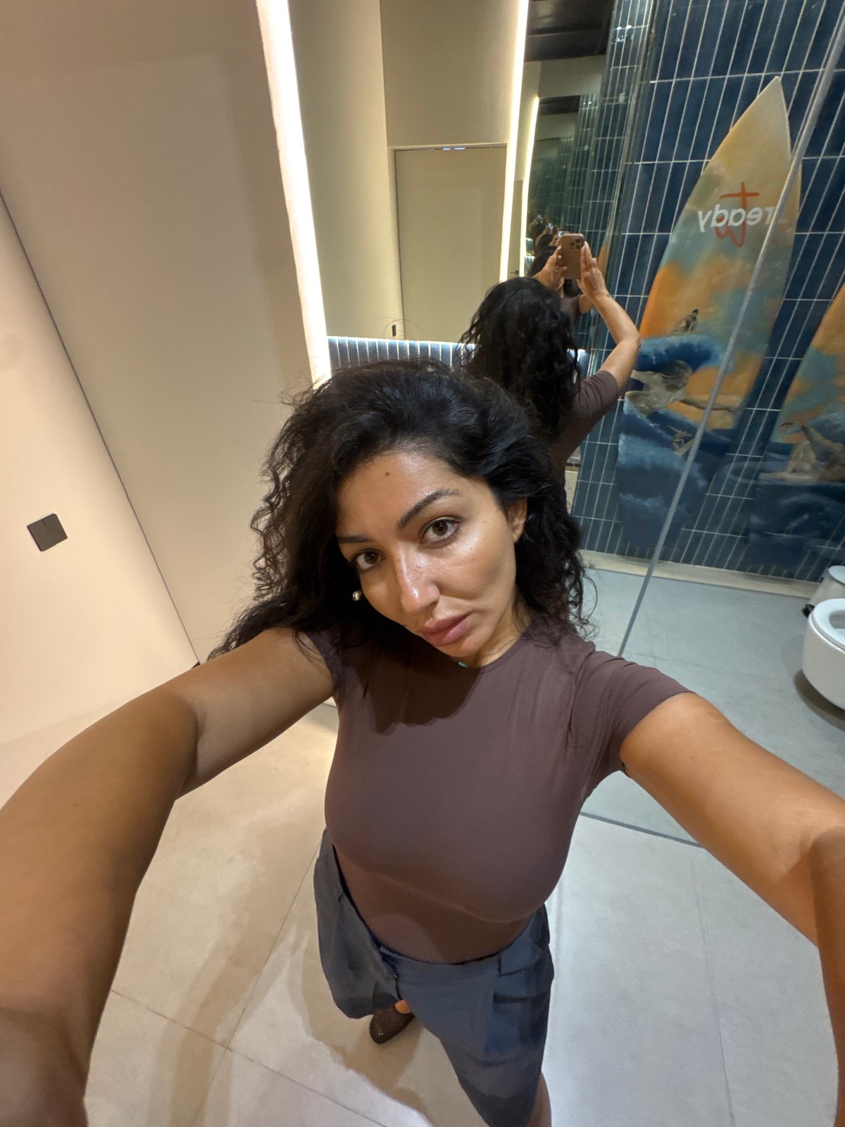 Woman Takes Mirror Selfies in Surfboard-Decorated Bathroom in Kuta