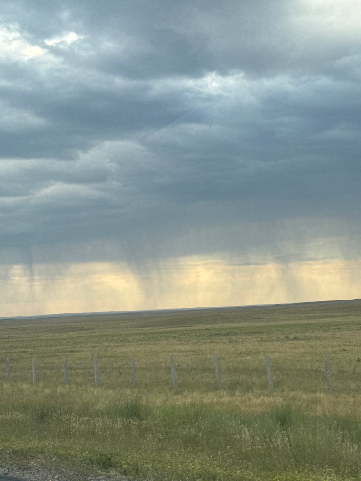 Rain shafts cut through an overcast Kazakhstan steppe sky
