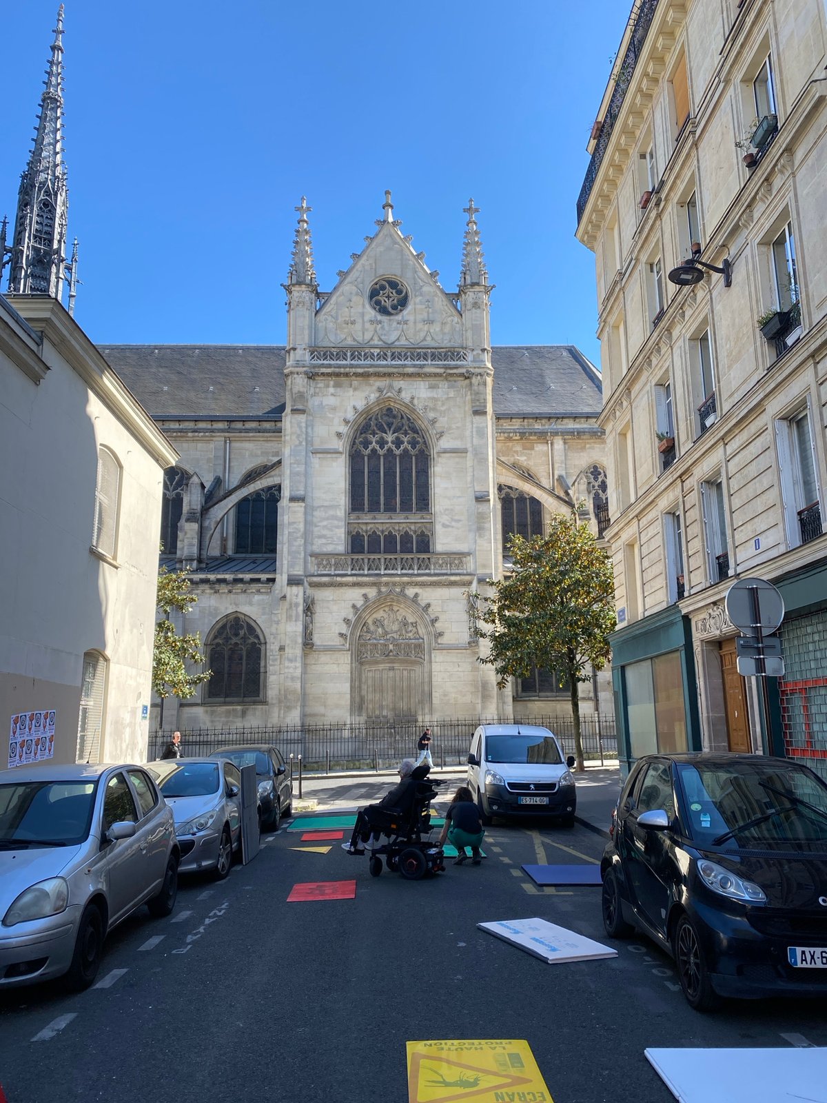 Sunny Paris street scene features prominent Gothic church
