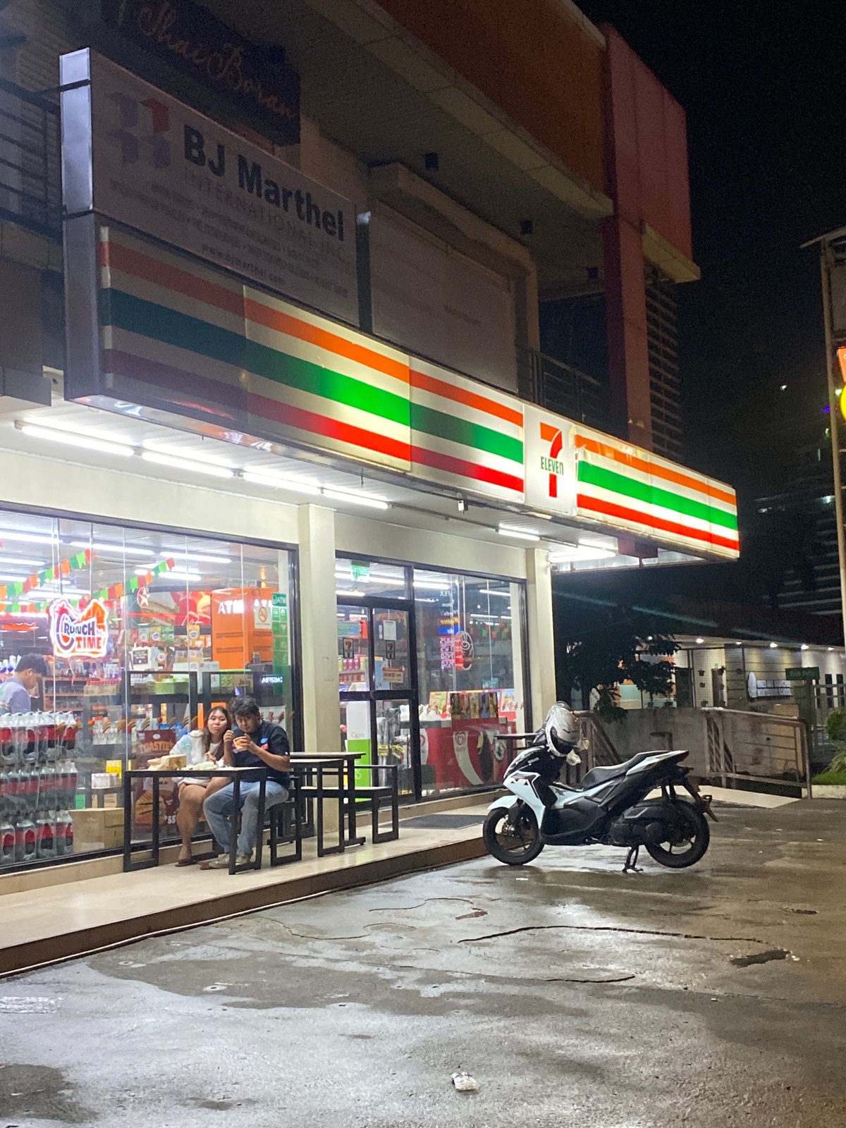 Wet Davao City streets at night, commercial strip in motion
