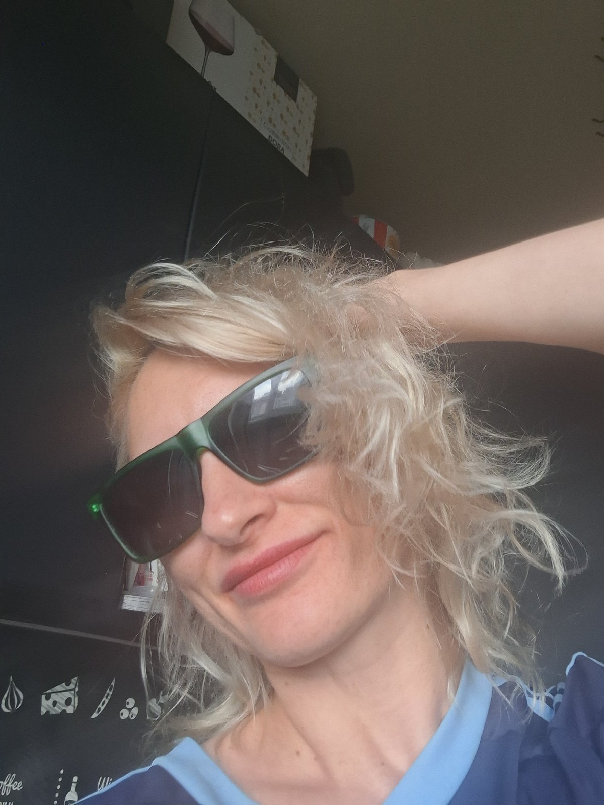 Indoor selfie series in a navy jersey and green sunglasses.