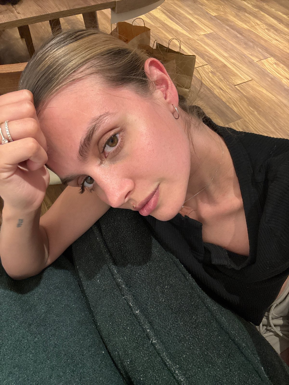 Person rests on wooden floor with shopping bag nearby