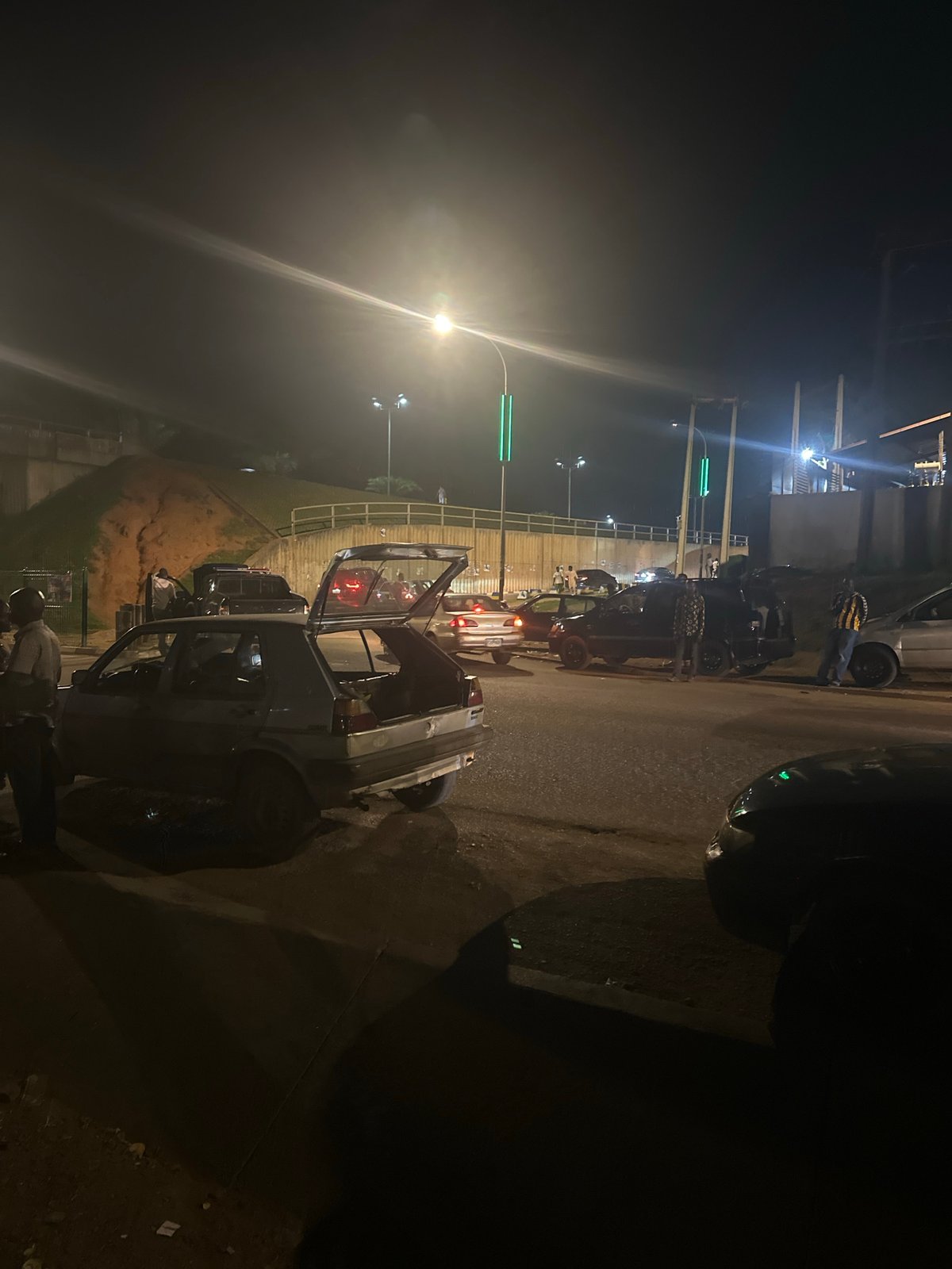 Nighttime street activity along a busy Abuja road corridor