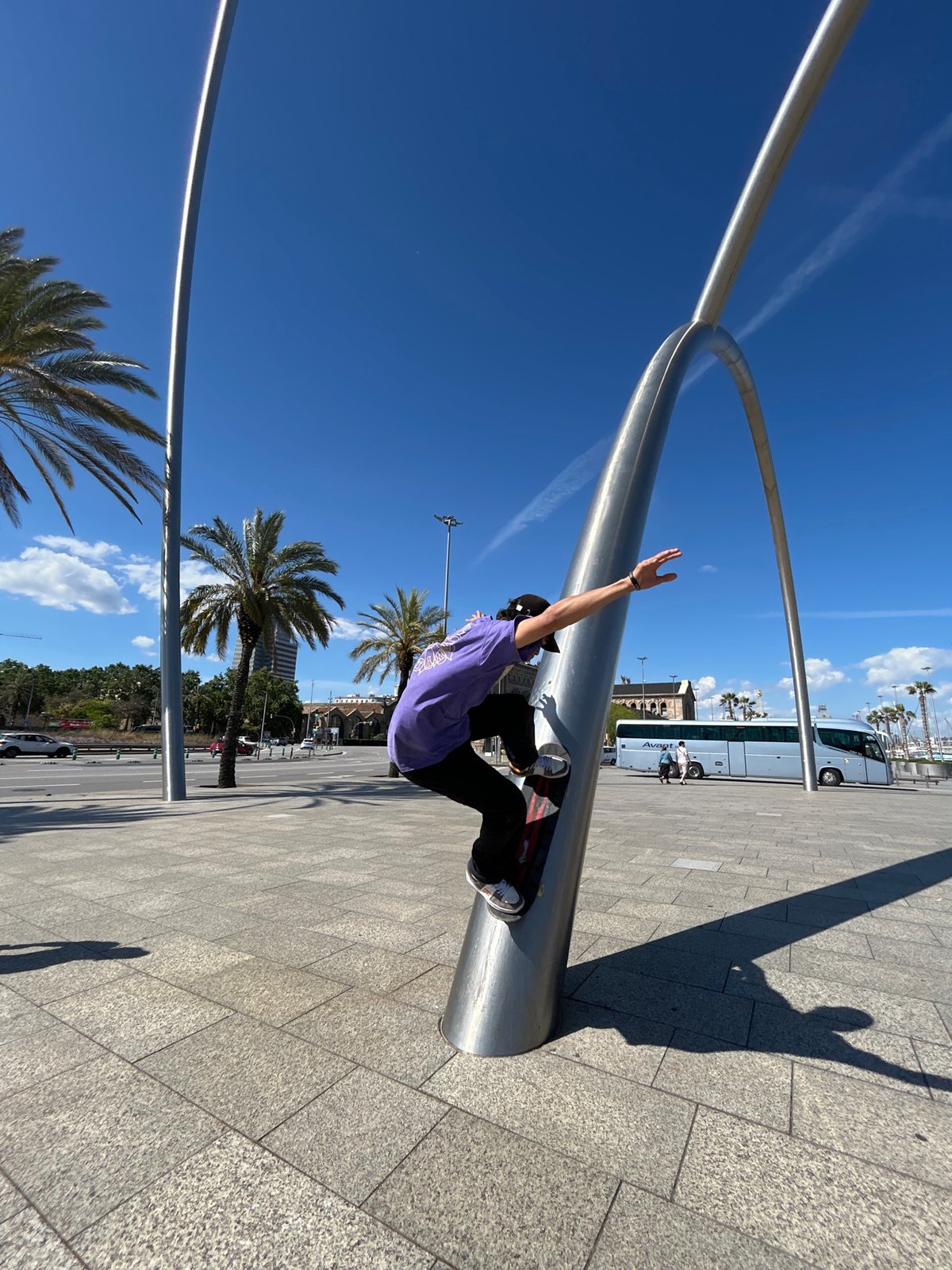 Skateboarder performs tricks in Barcelona plaza on sunny afternoon