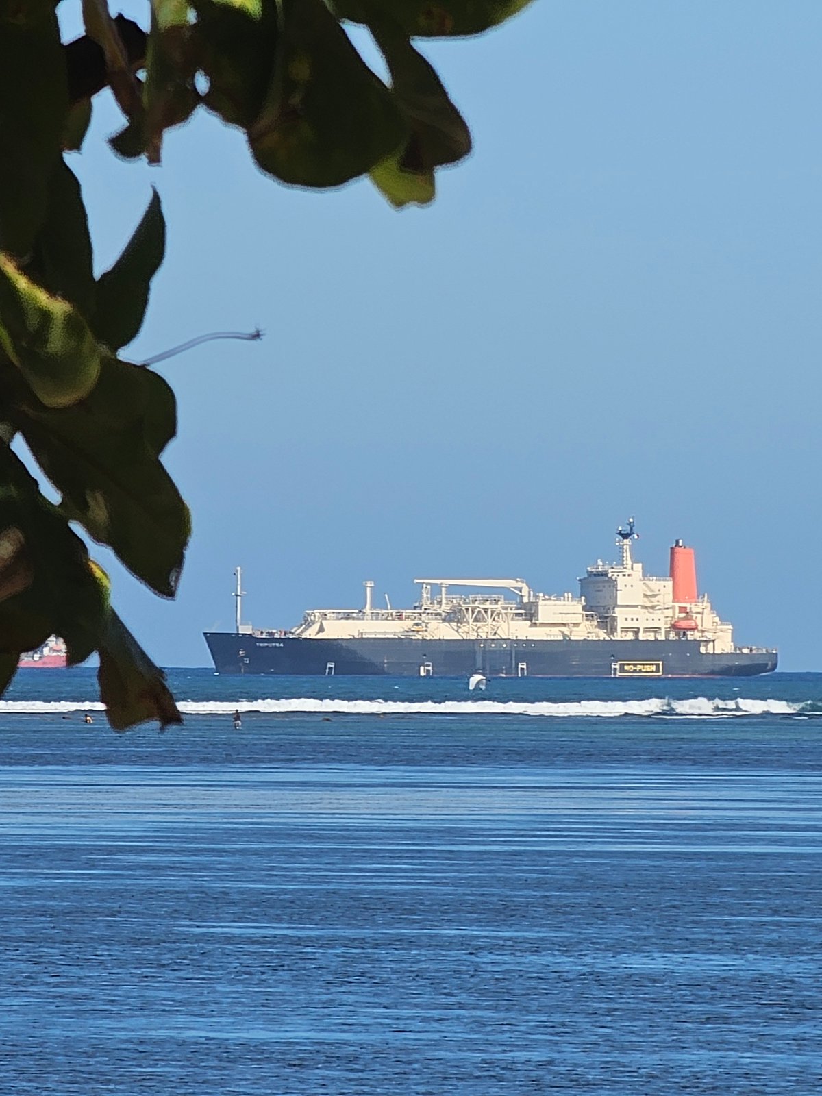 Jukung boats and cargo ships along a Bali morning shoreline