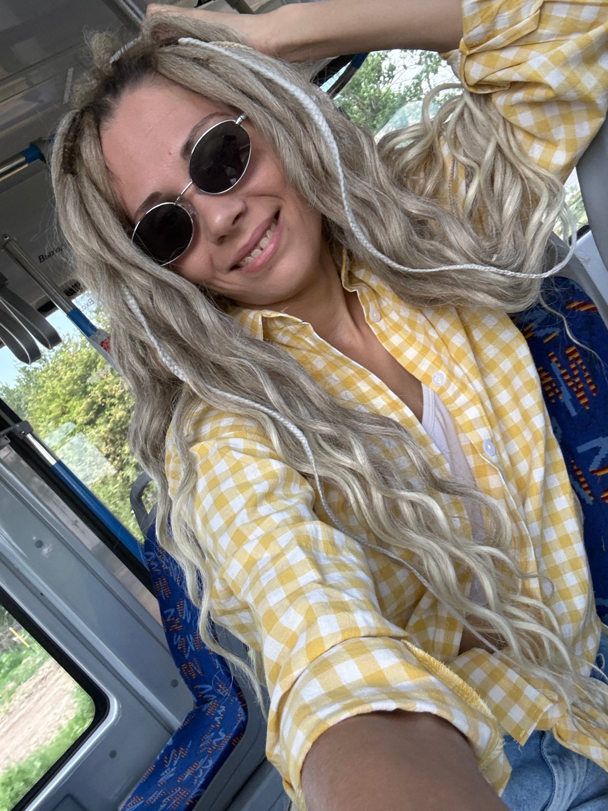 Woman with dreadlocks smiles on bus in Rusanovo