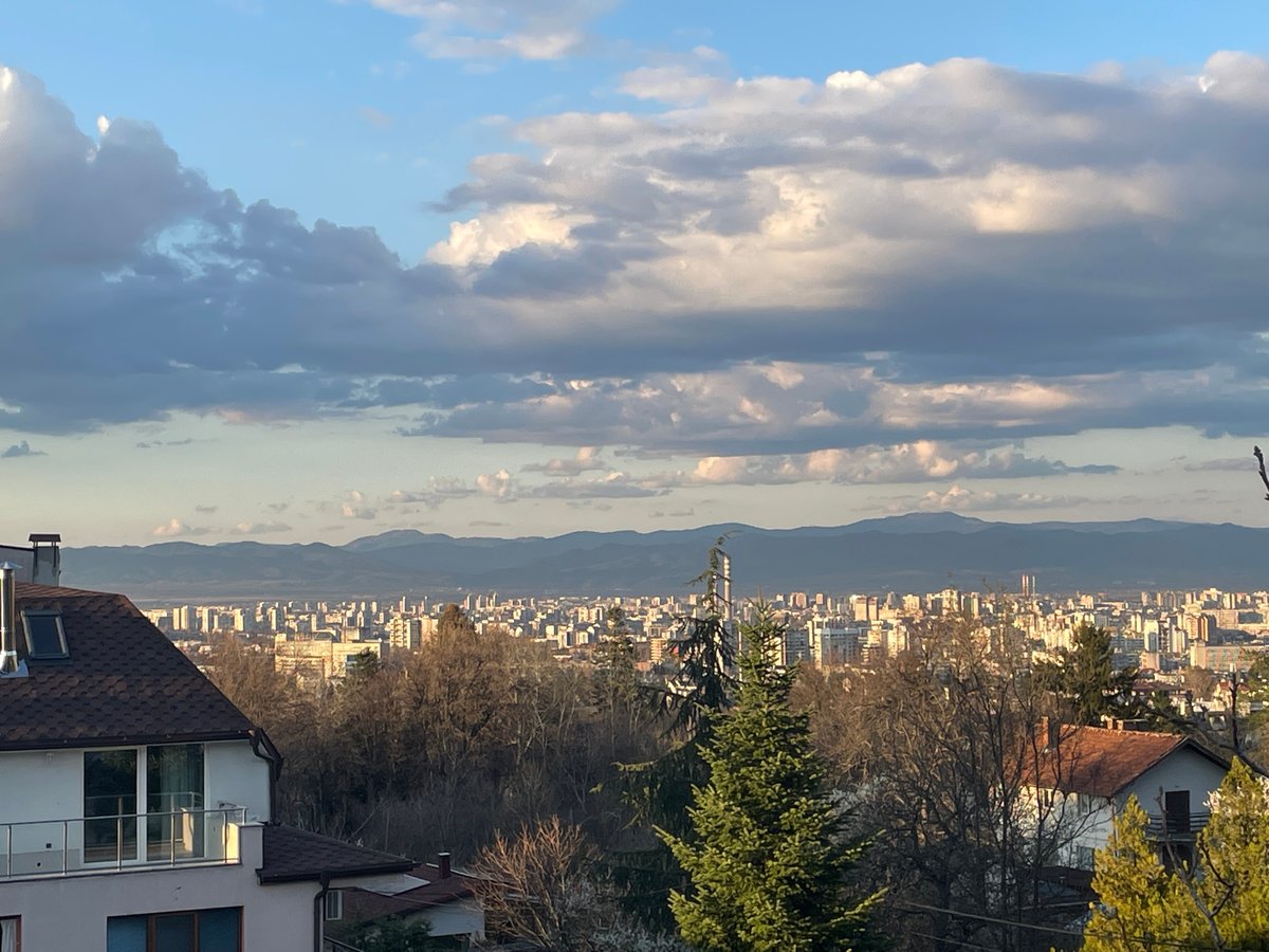 Sofia cityscape documented under cloudy skies with mountain backdrop