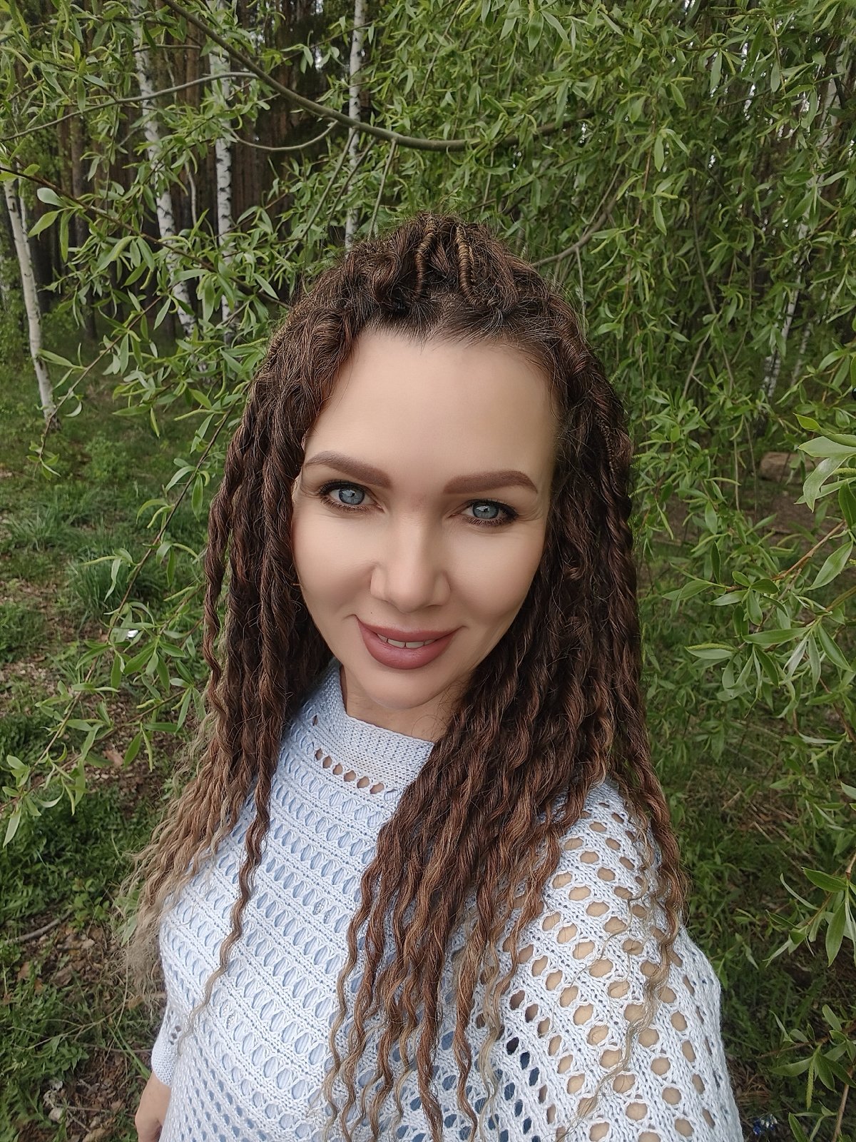 Woman takes selfies by waterside in blue sweater
