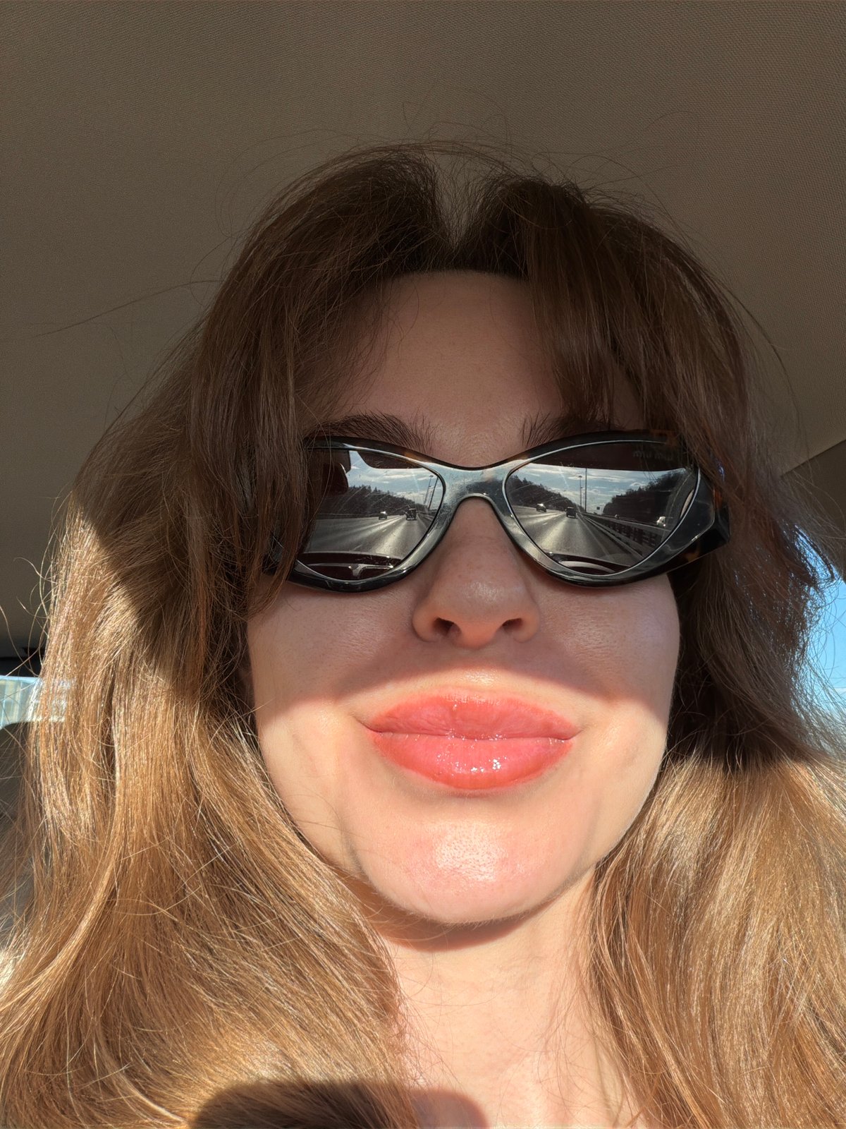 Woman in sunglasses rests in car in Davydkovo