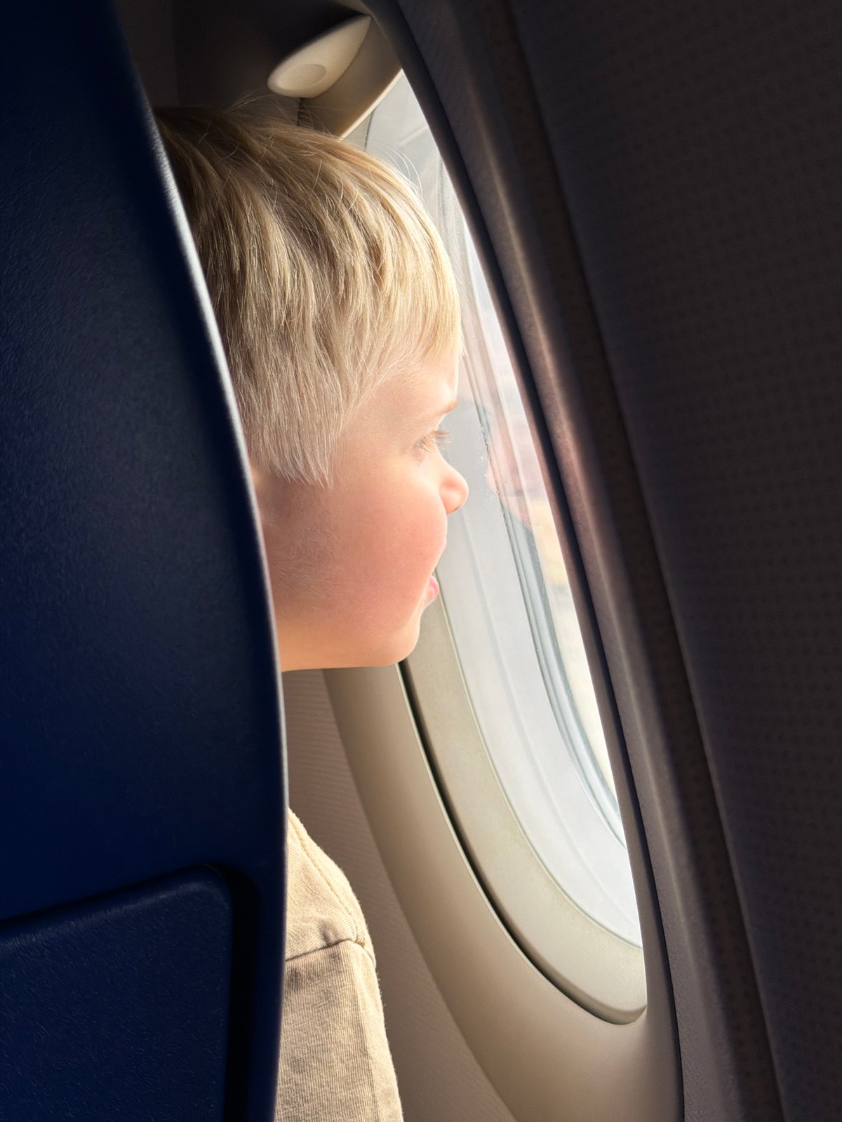 Child rests against airplane seat near window in Russia
