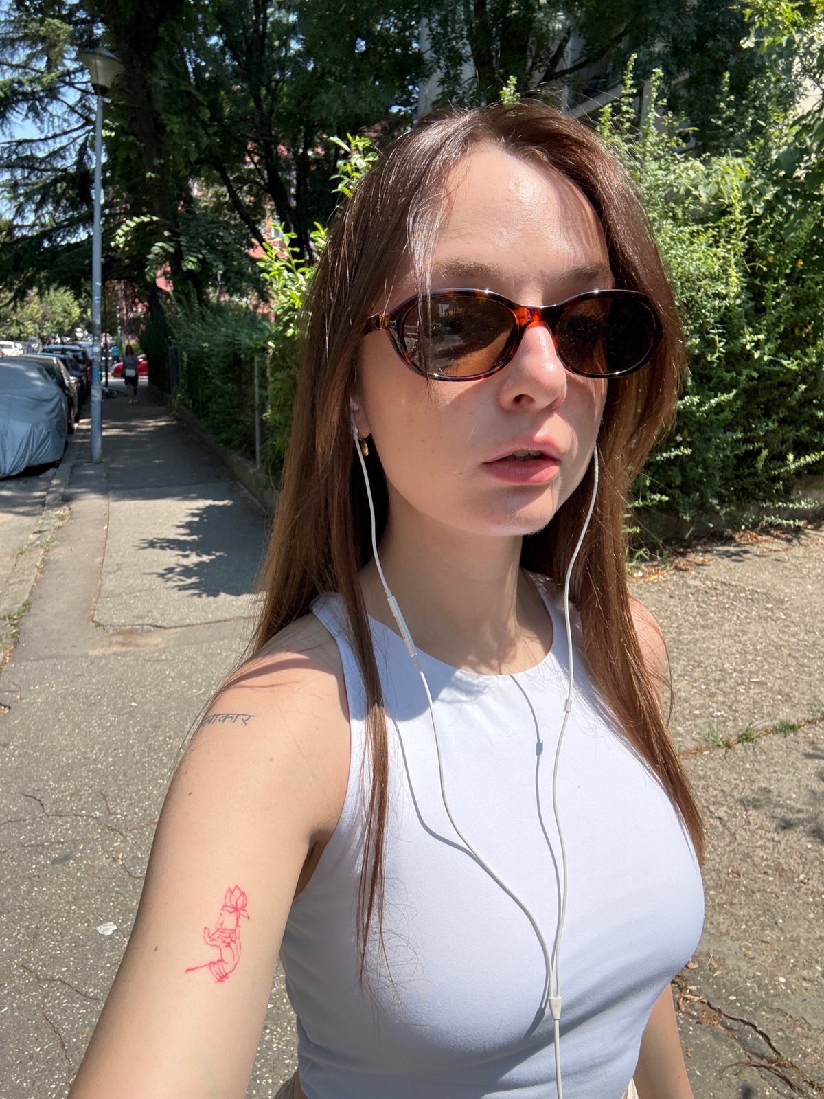 Sunny selfie moment in Belgrade, white earbuds and lotus tattoo